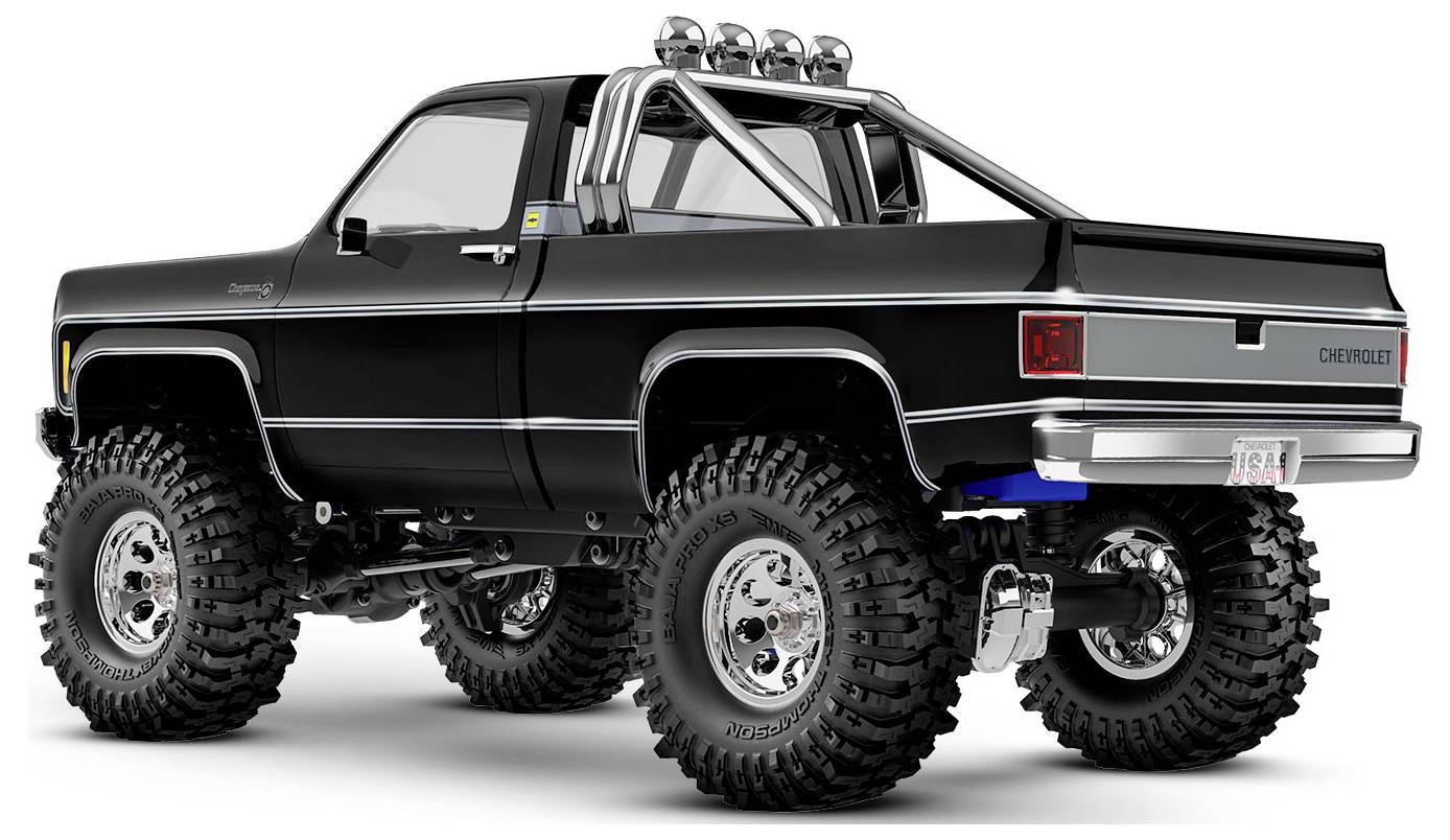 Un camion tout-terrain noir avec de grands pneus et des détails chromés, vu de dos, mettant en valeur sa structure robuste et sa suspension surélevée.