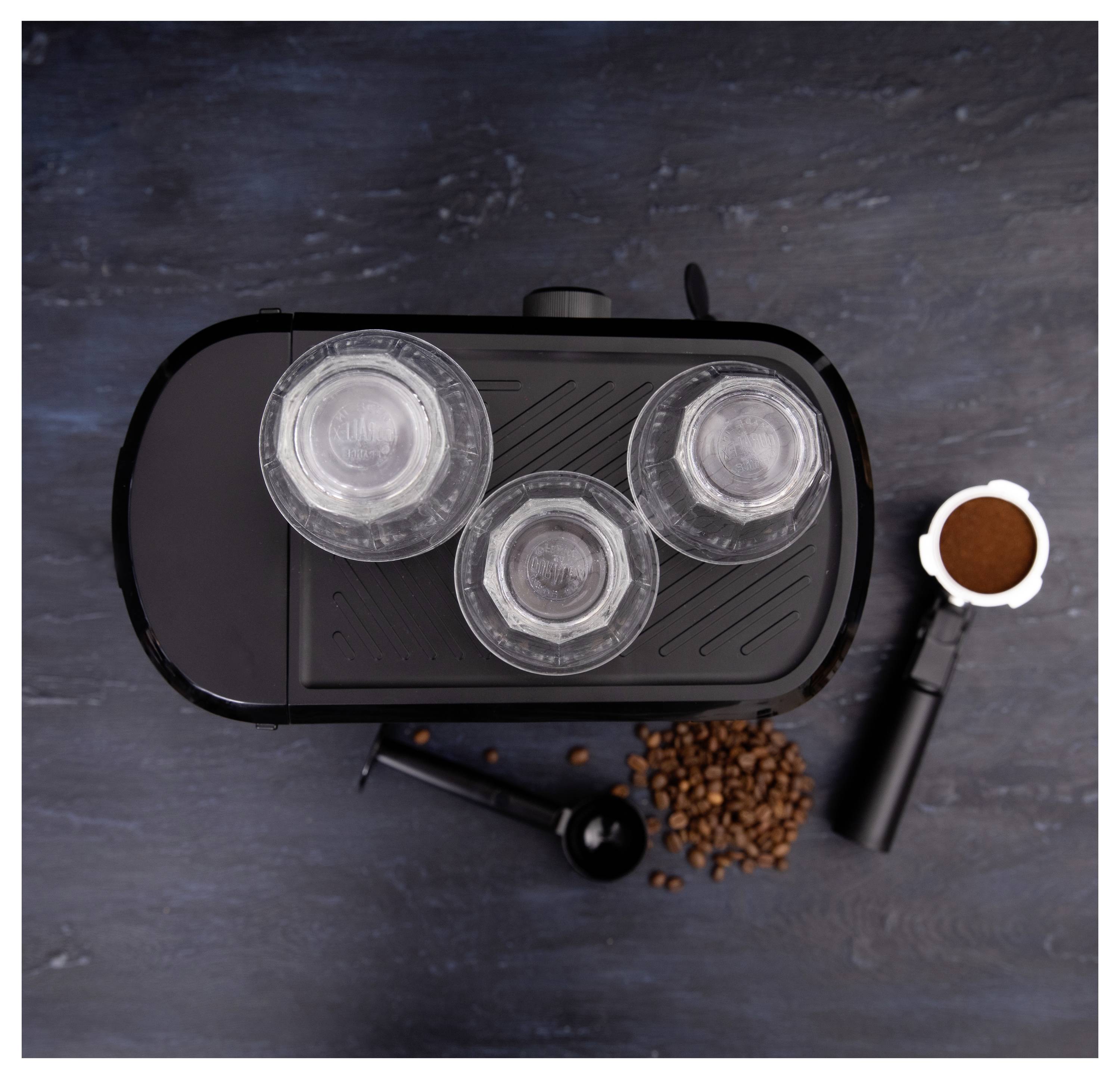 Vue de dessus d'une machine à café avec trois couvercles transparents, entourée de grains de café, d'une cuillère doseuse et d'un porte-filtre rempli de café moulu.