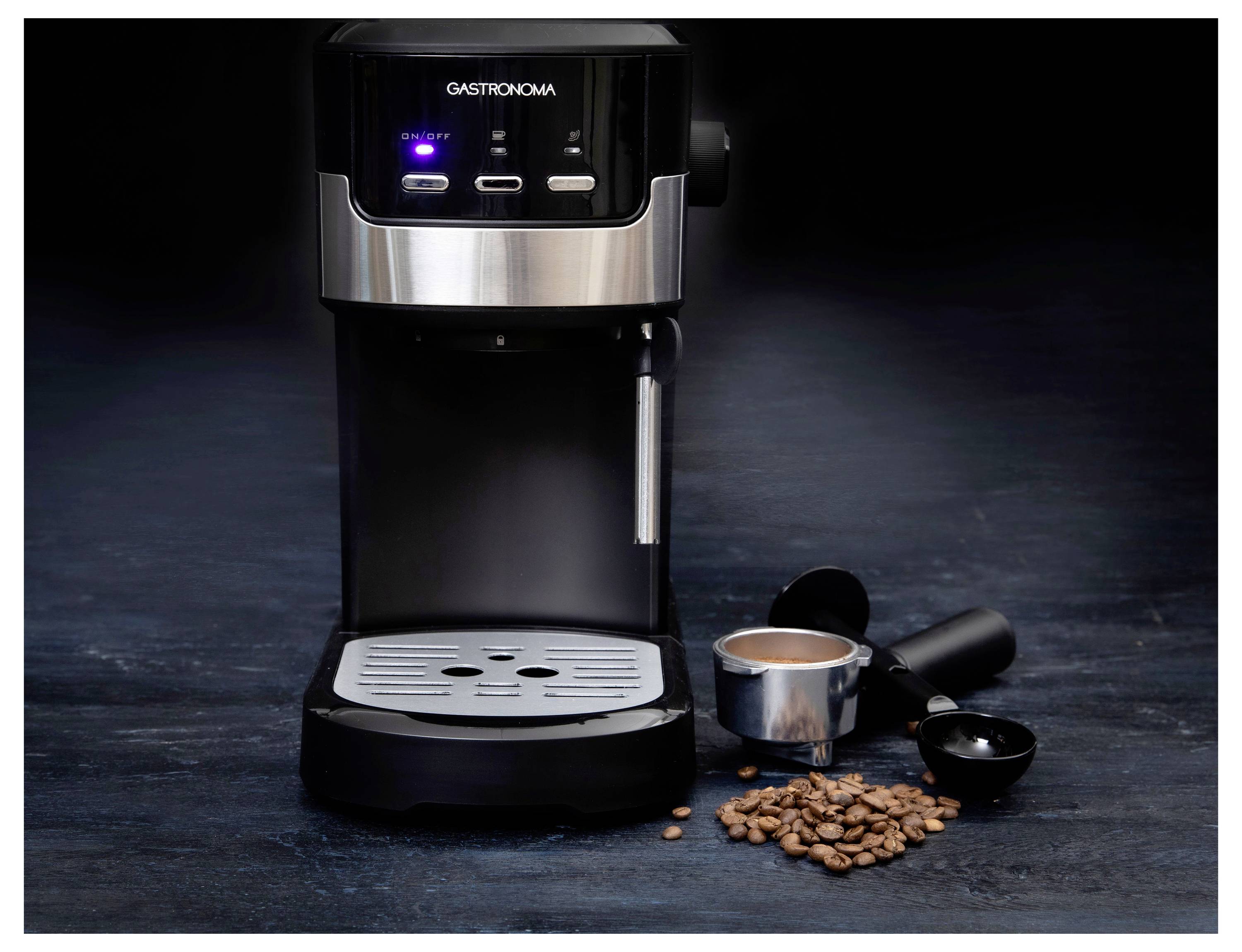 Machine à espresso sur une surface sombre avec un porte-filtre, du café moulu et des grains à proximité, suggérant la préparation du café.