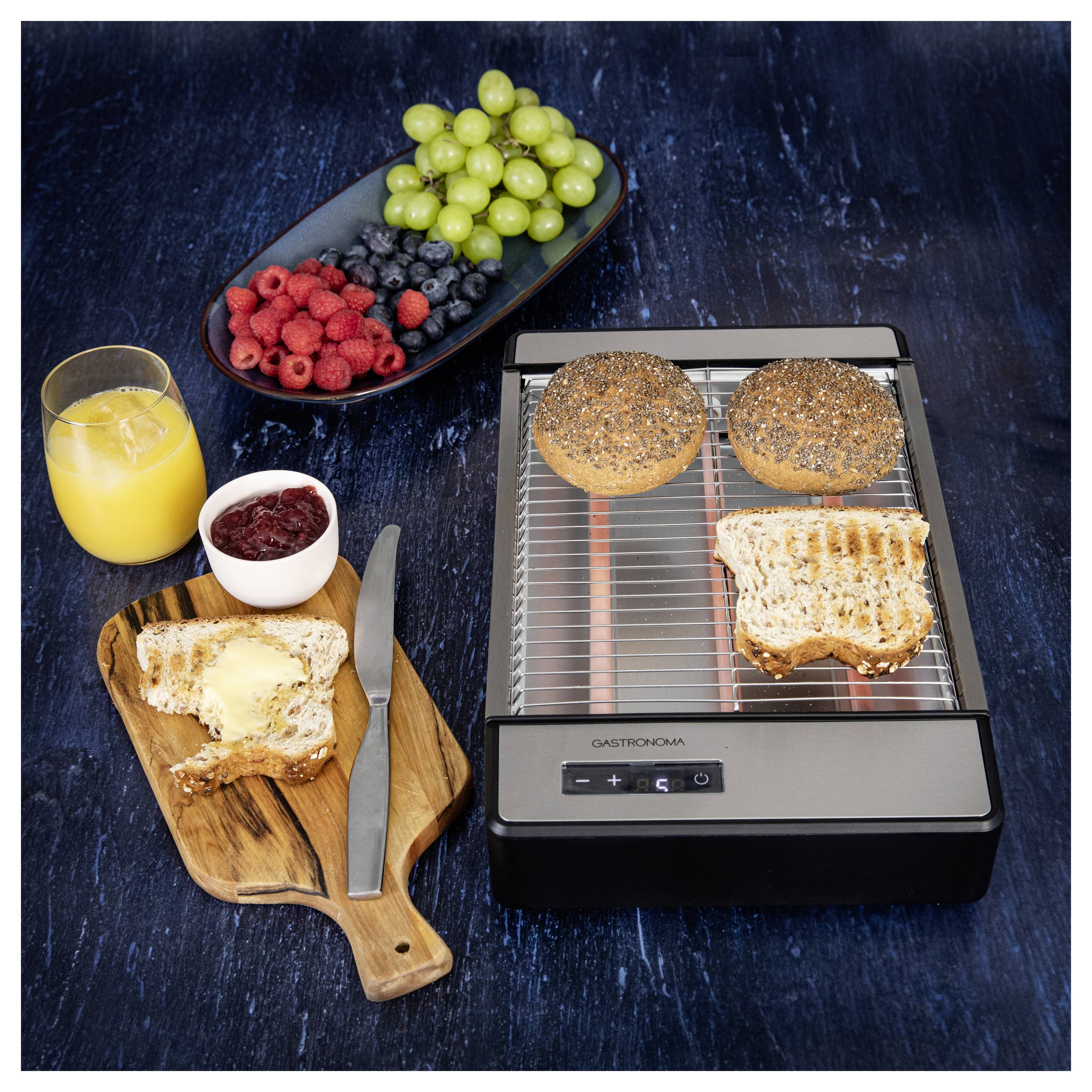 «Étale de petit-déjeuner avec un grille-pain, bagels grillés, toast beurrés, couteau, confiture, baies fraîches, raisins et un verre de jus d'orange.»