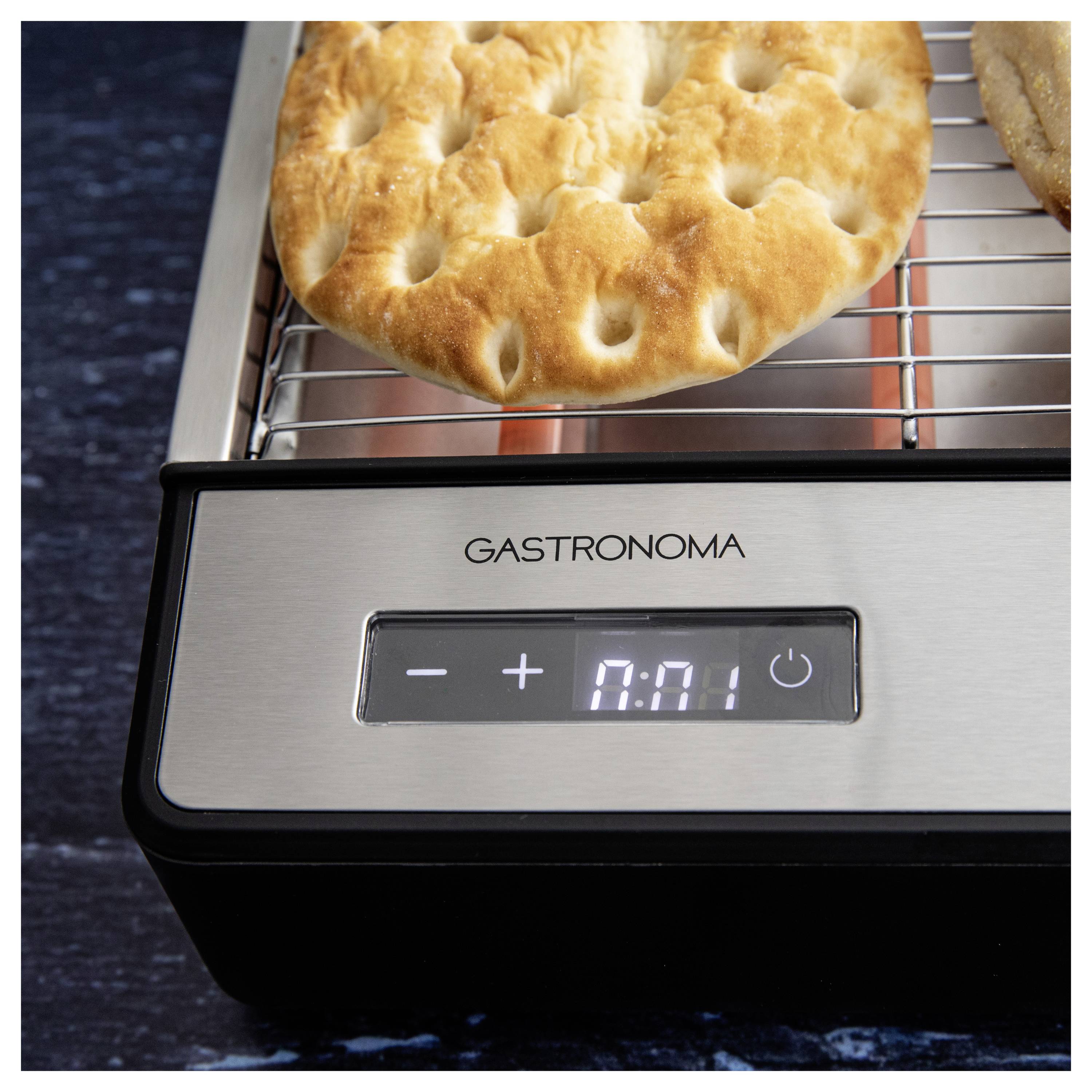 Une galette avec des trous est en train d'être grillée sur une plaque électrique avec un minuteur numérique affichant '0:01'.