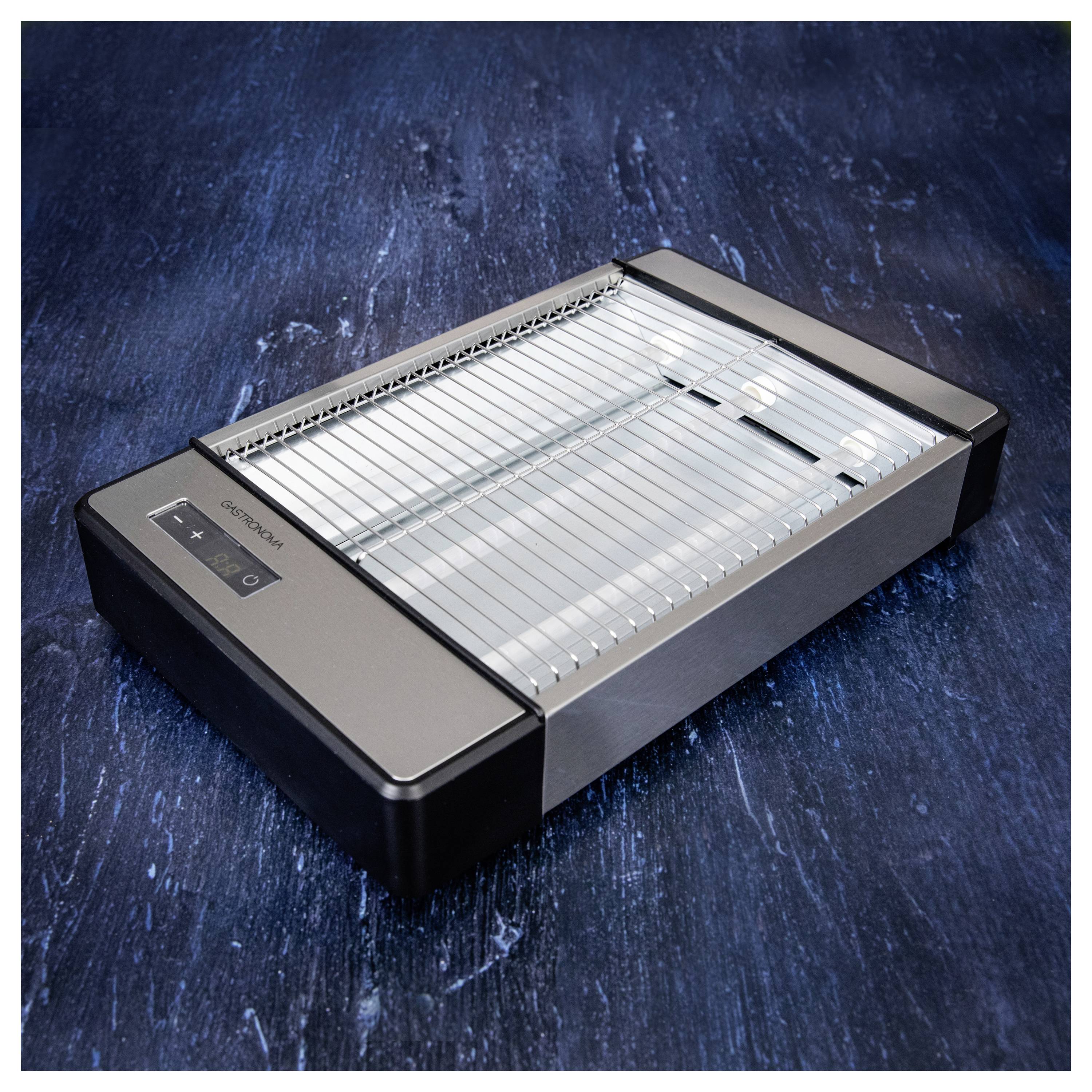 Un gril électrique en acier inoxydable doté d'un panneau de commande numérique et au design épuré, posé sur une surface texturée sombre.