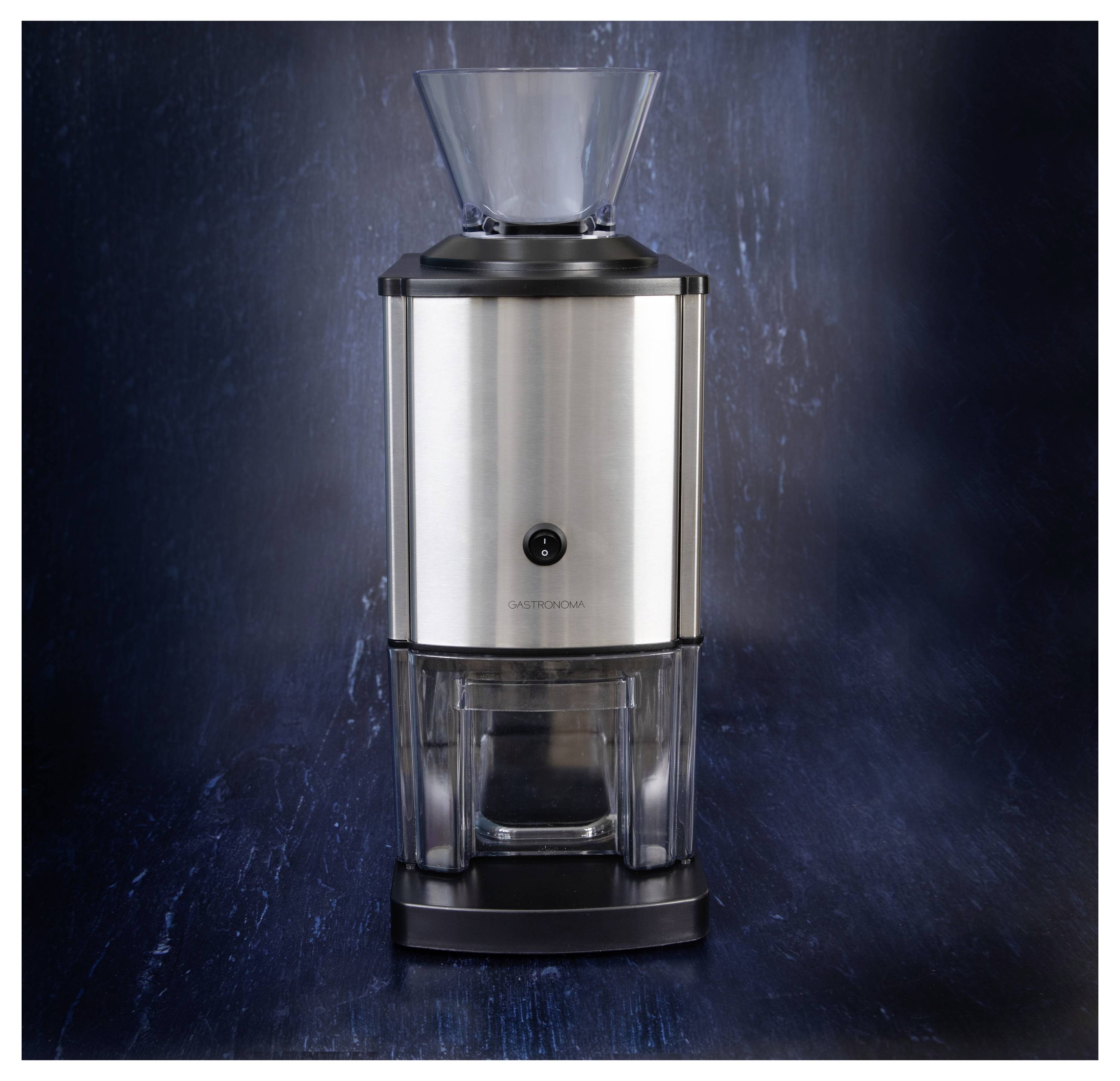 Un moulin à café électrique en argent et noir avec un couvercle et une base transparents, placé contre un arrière-plan texturé sombre.