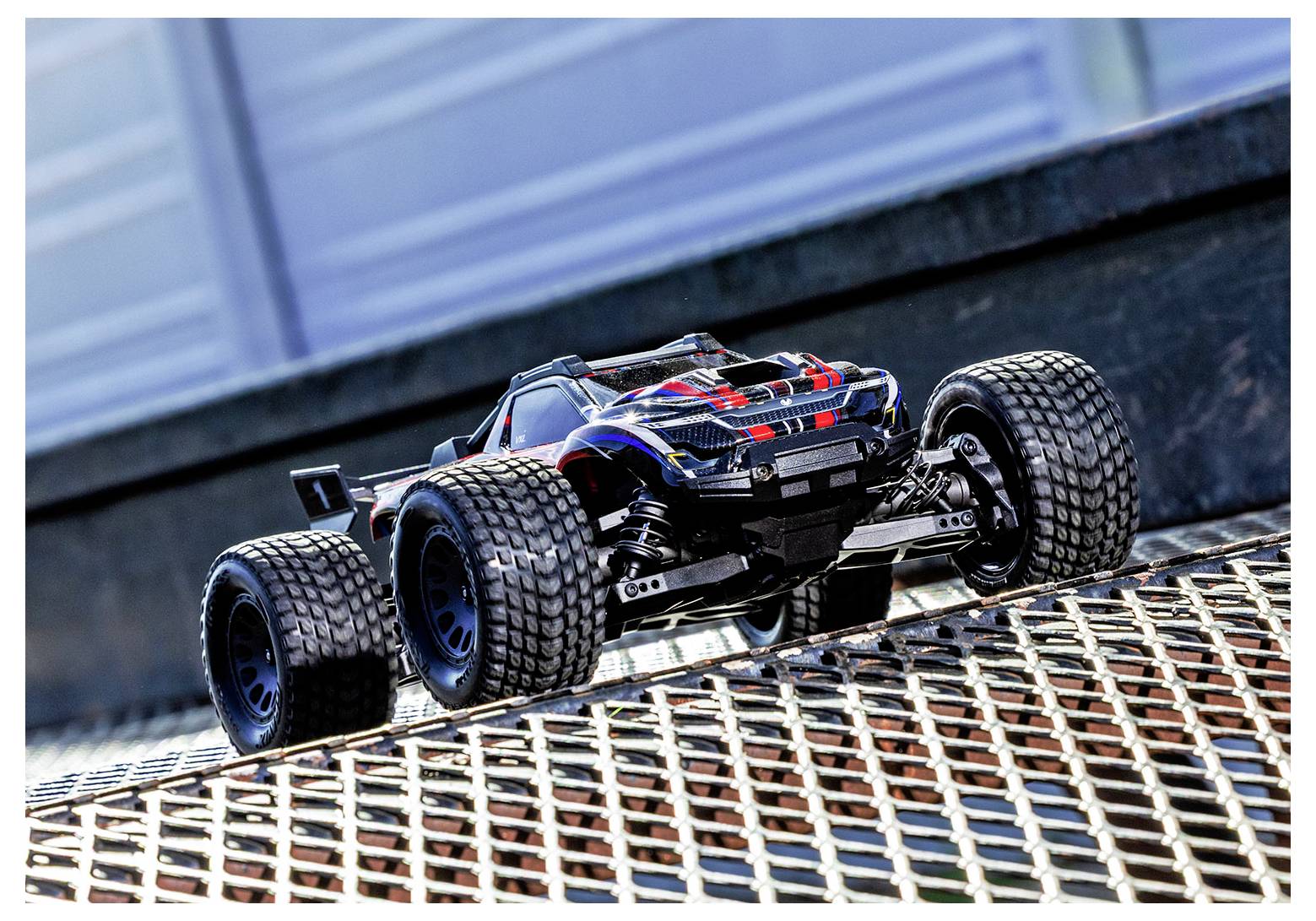 Une voiture télécommandée sur une rampe en grille métallique, mettant en évidence la construction robuste du véhicule et ses capacités tout-terrain.