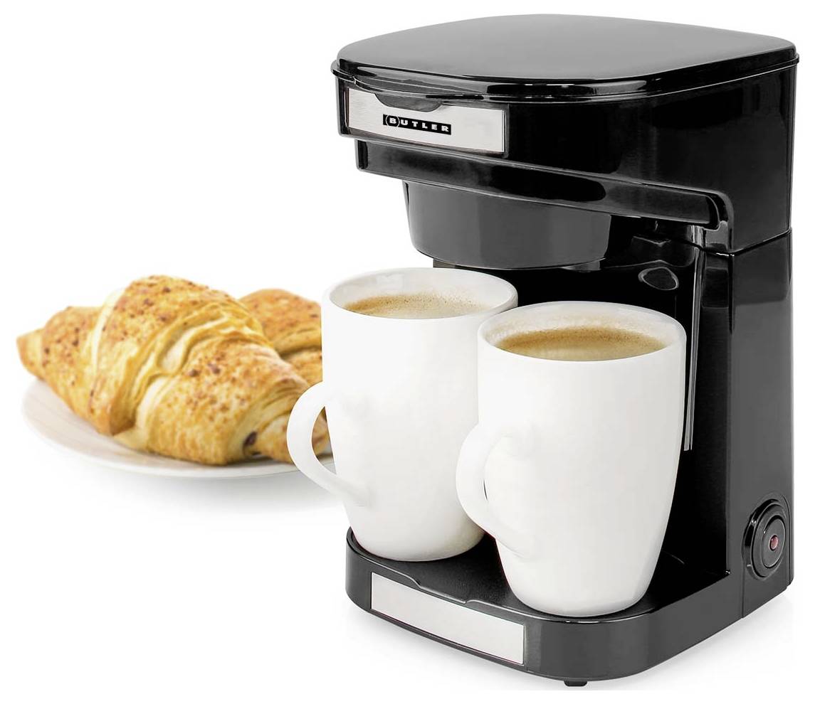 Un cafetière noire avec deux tasses blanches remplies de café, à côté d'une assiette avec deux croissants.