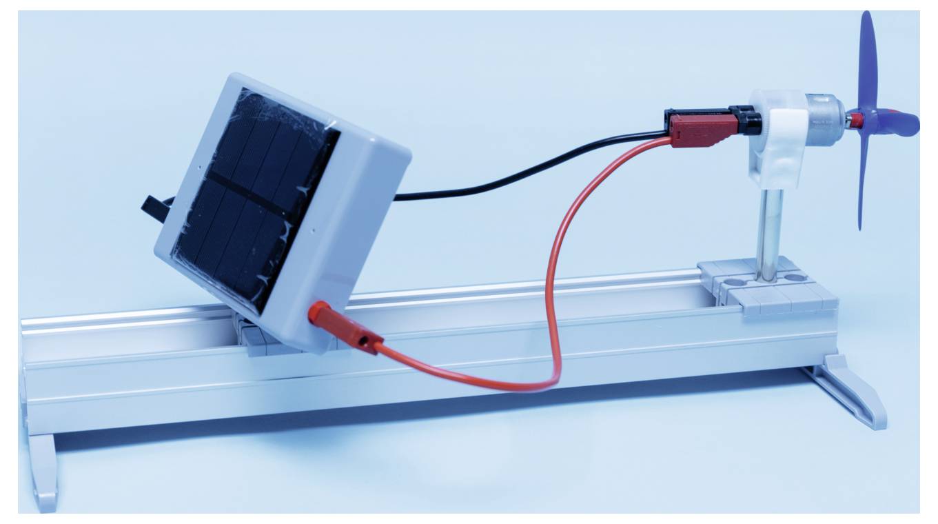 A small solar panel is connected to a mini wind turbine on a metallic stand, demonstrating a renewable energy setup.