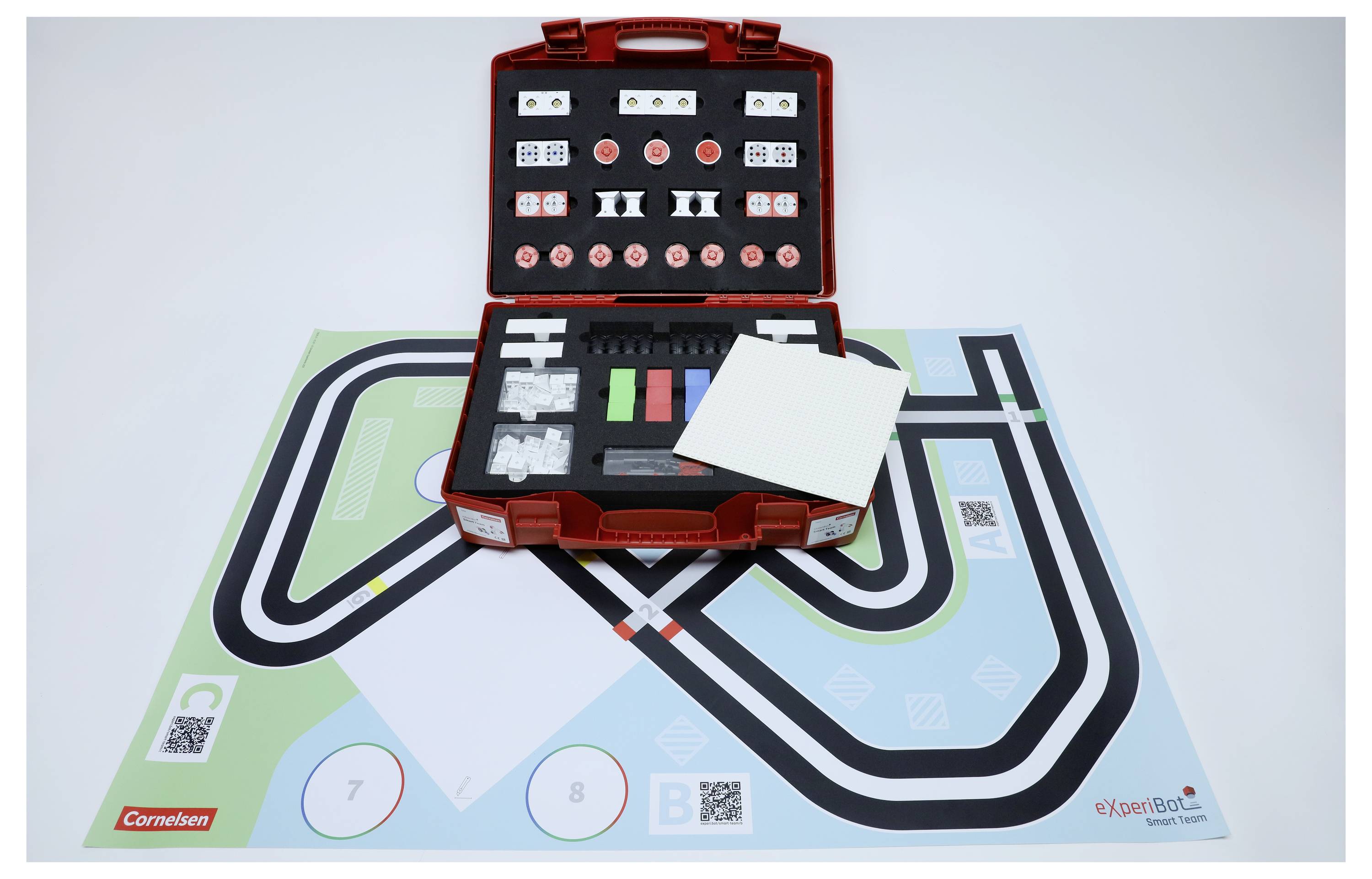 A red toolkit containing various components is displayed on a mat with a track layout, used for educational or experimental purposes.