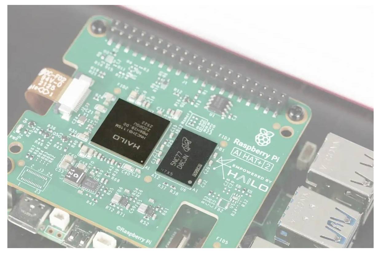 Gros plan d'un module Raspberry Pi AI Hat présentant une carte de circuits imprimés verte avec des puces noires portant les étiquettes « HAILO » et « AI HAT 2 ».