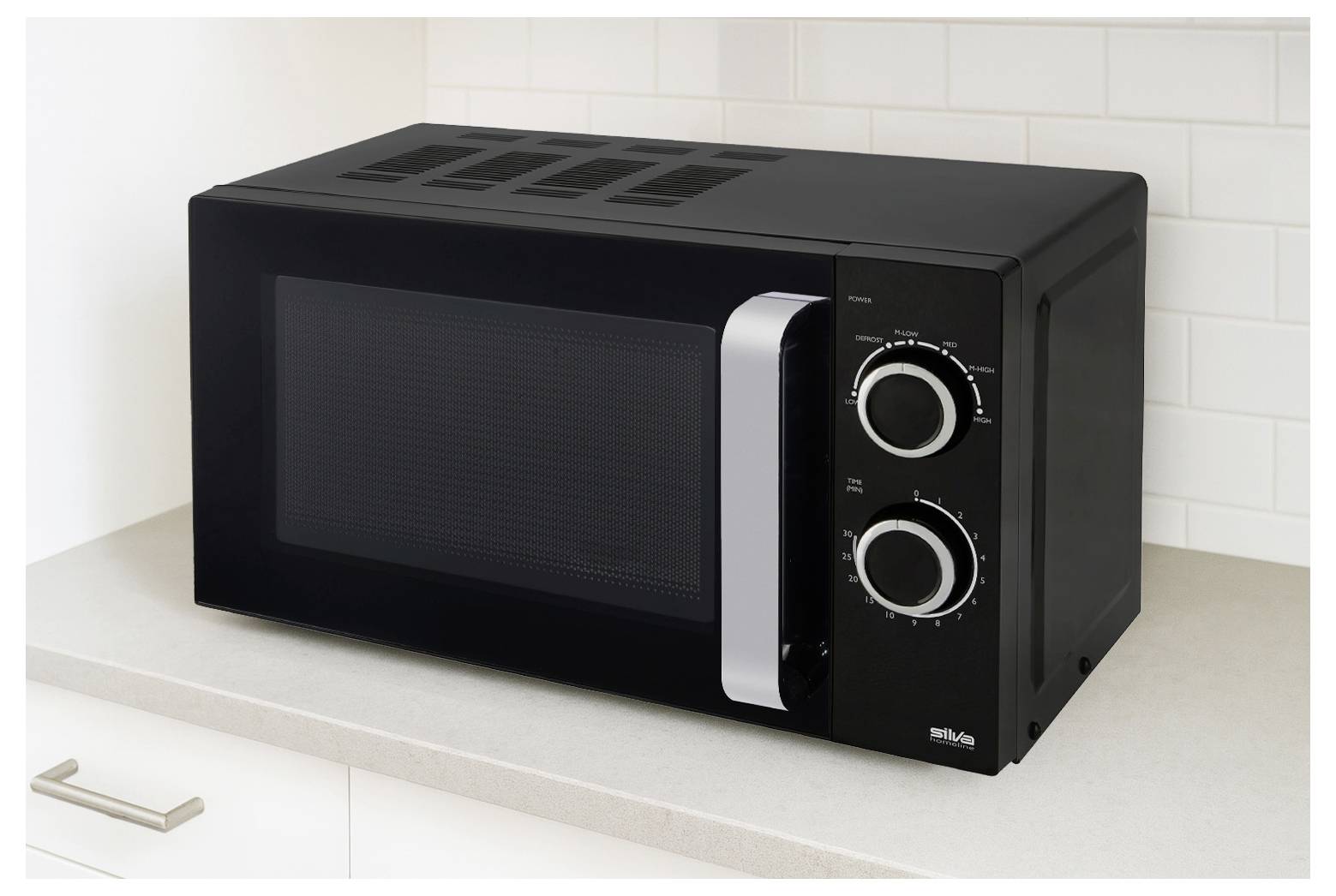 Un four à micro-ondes noir avec deux cadrans de contrôle circulaires est posé sur un comptoir de cuisine devant un carrelage blanc en crédence.