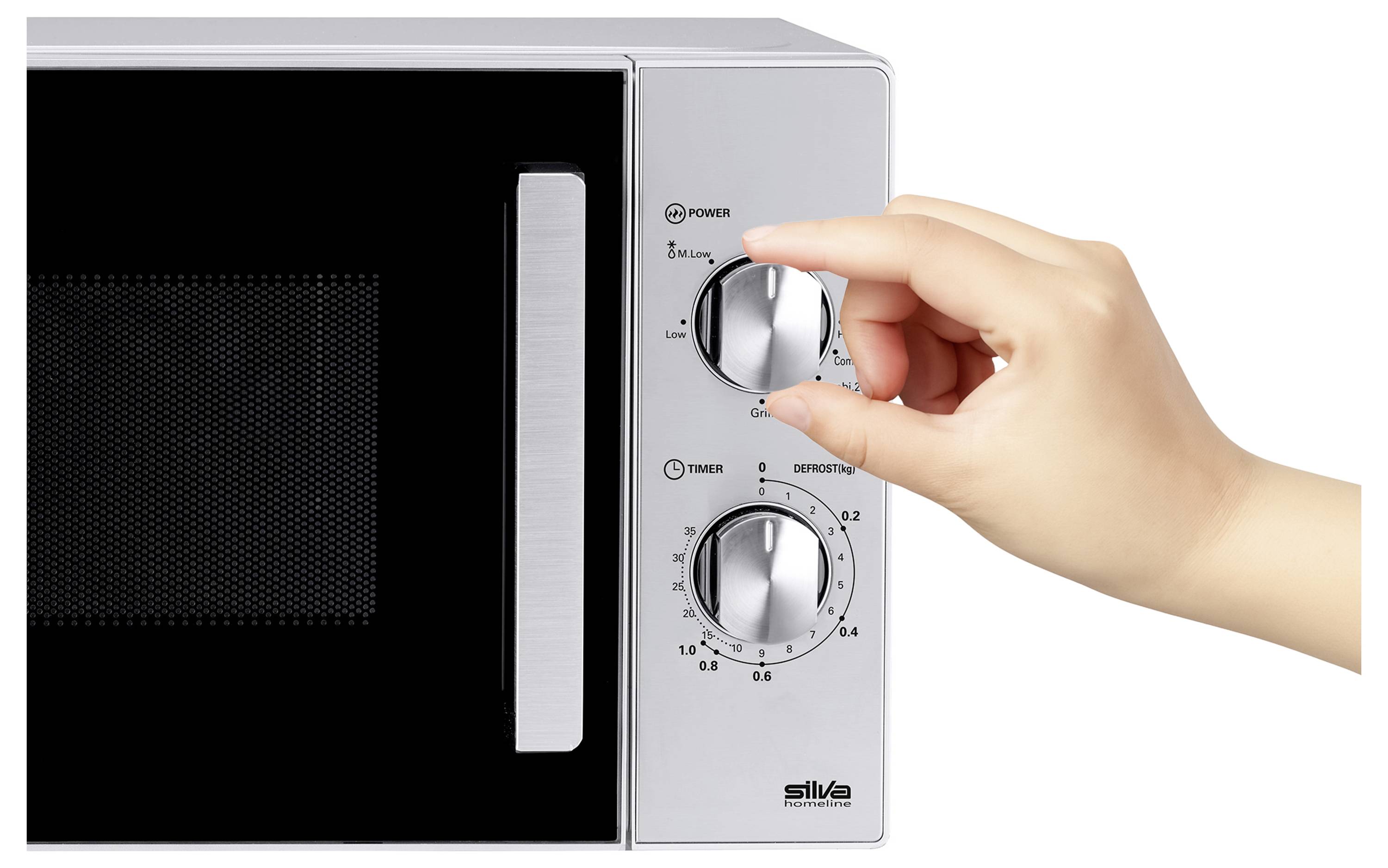 Une main ajustant le cadran sur un micro-ondes argenté, se concentrant sur le réglage du niveau de puissance et du minuteur.