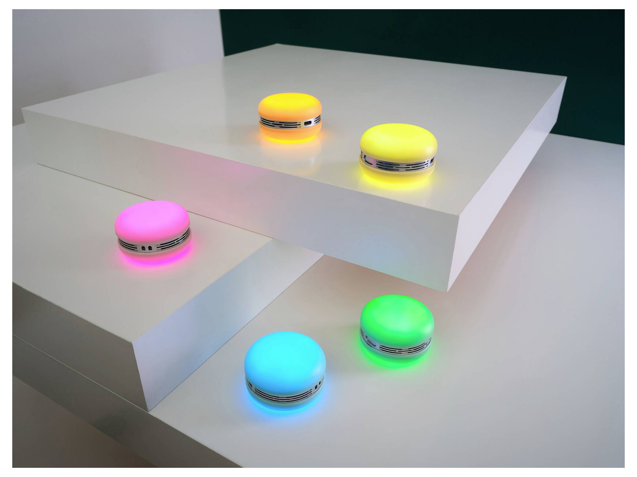 Cinq lumières LED rondes multicolores sur des plateformes blanches en gradins, luisant en rose, jaune, bleu, vert et orange, créant un effet d'ambiance.