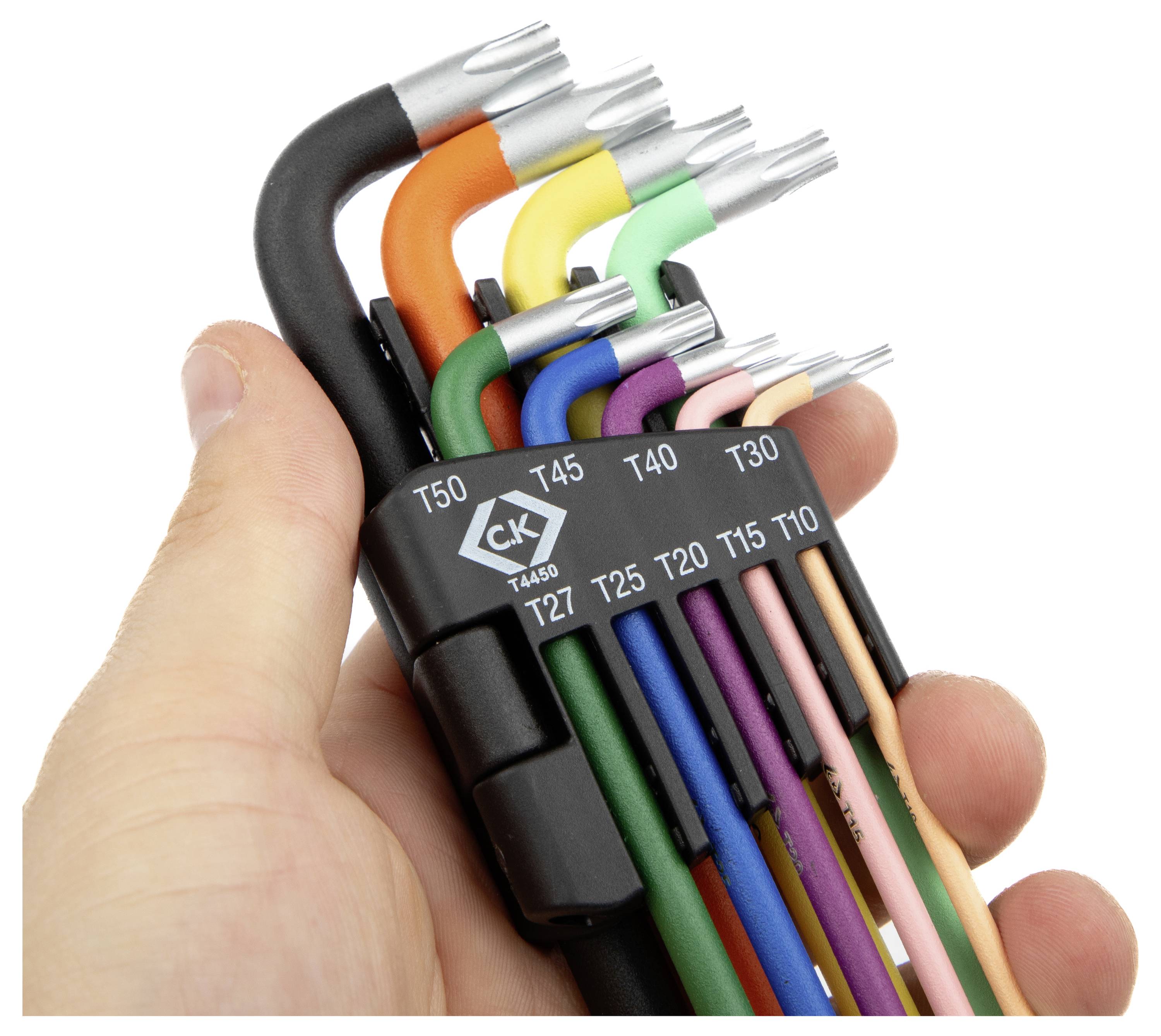 Une main tient un ensemble de clés hexagonales colorées, chacune étiquetée avec des tailles T10 à T50, arrangées dans un support noir.
