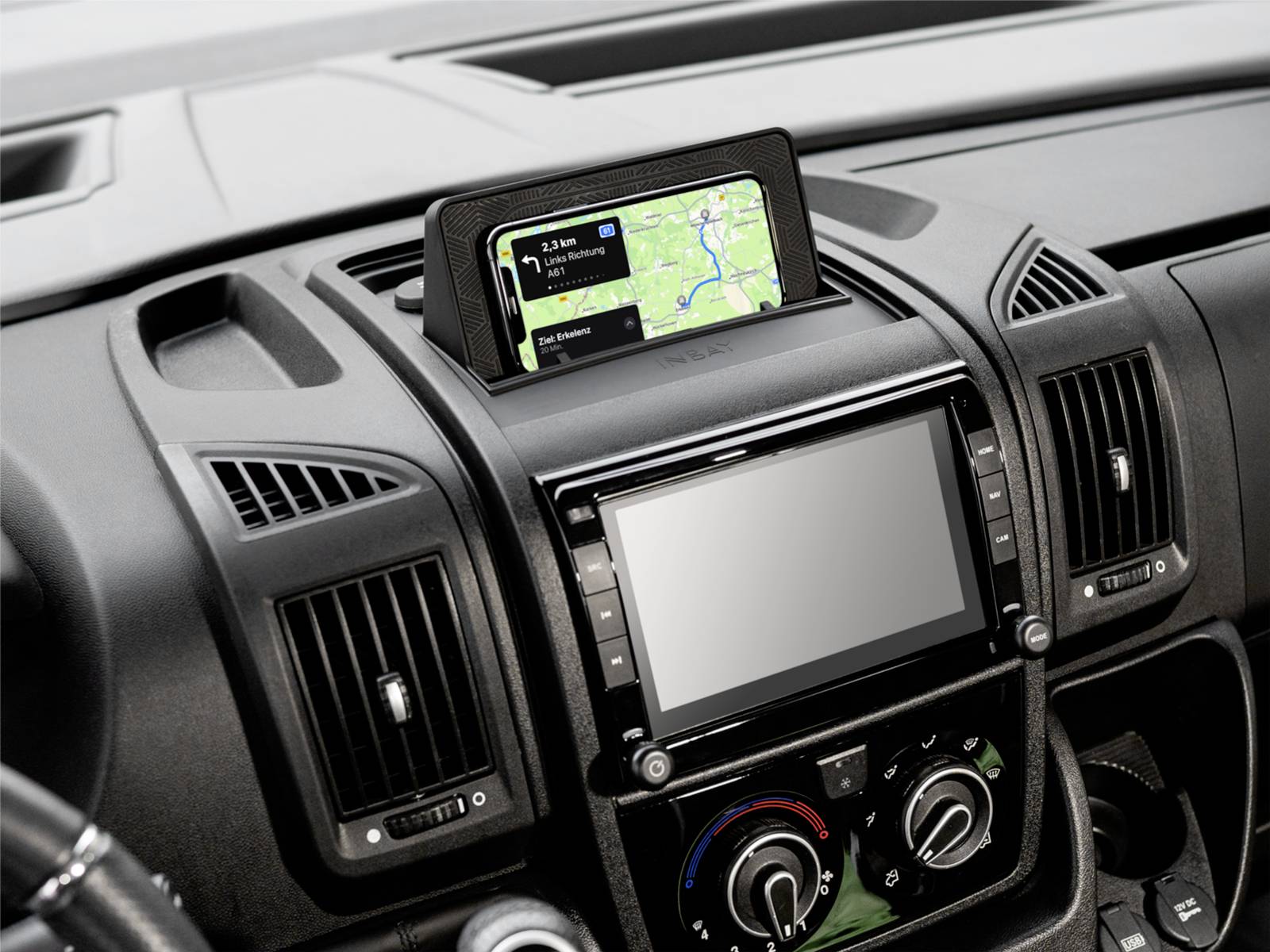 Car dashboard with a GPS navigation screen showing a route above a larger blank infotainment display and climate controls.