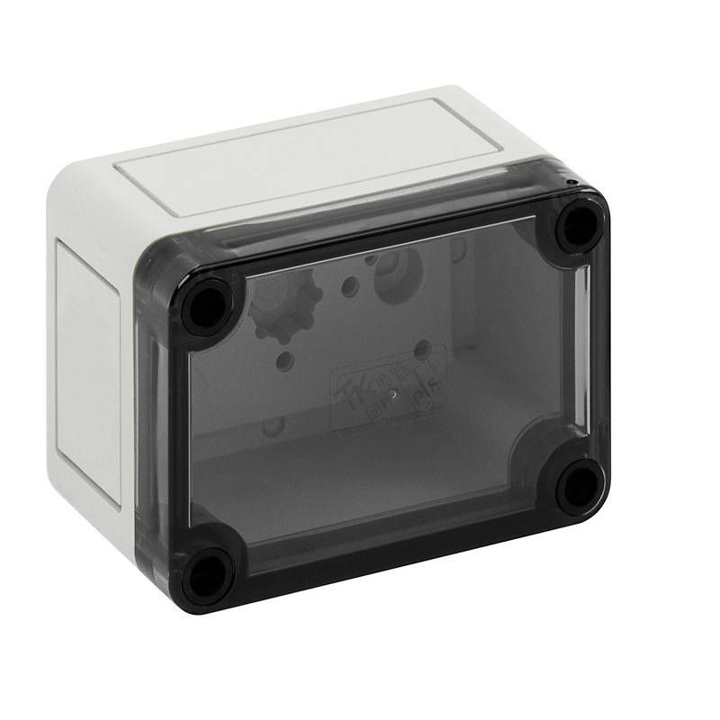 Boîtier électrique gris avec couvercle avant translucide foncé et quatre fixations à vis d'angle, présenté sur un fond blanc.