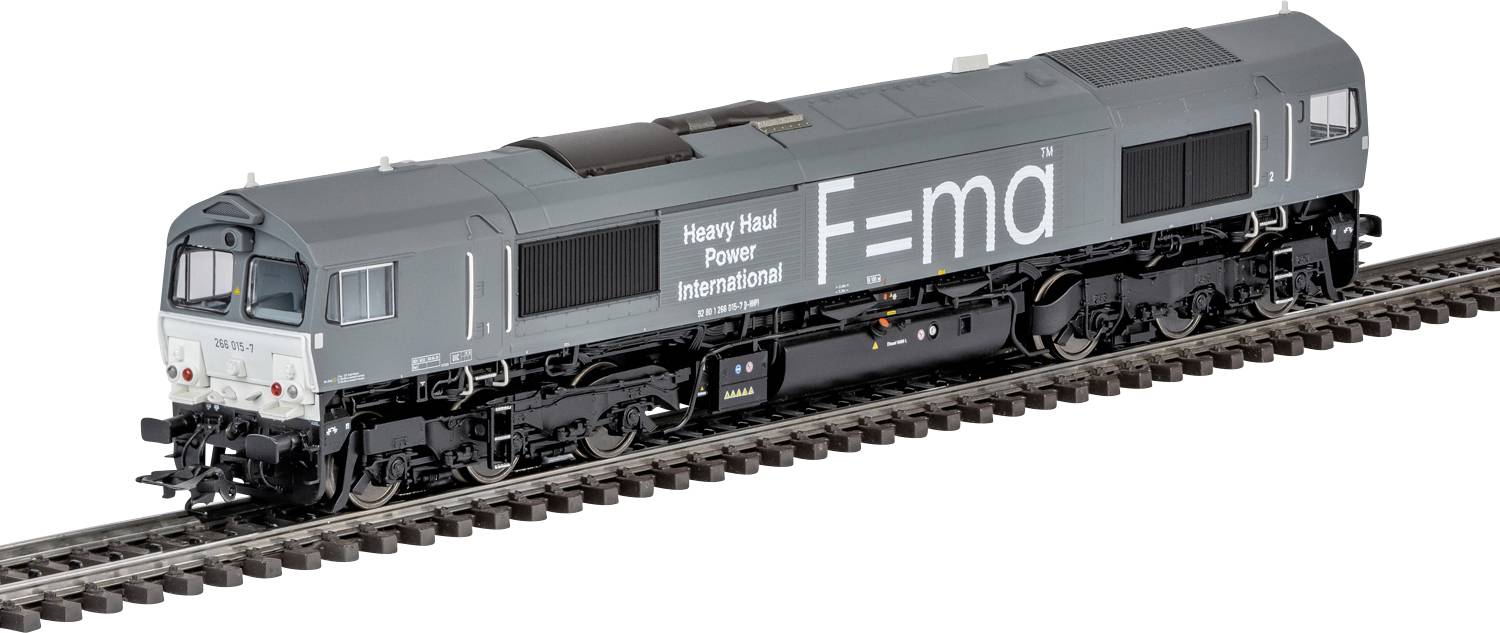 Une locomotive grise portant les inscriptions « Heavy Haul Power International » et « F=ma » circule sur des rails de chemin de fer, soulignant un transport puissant.