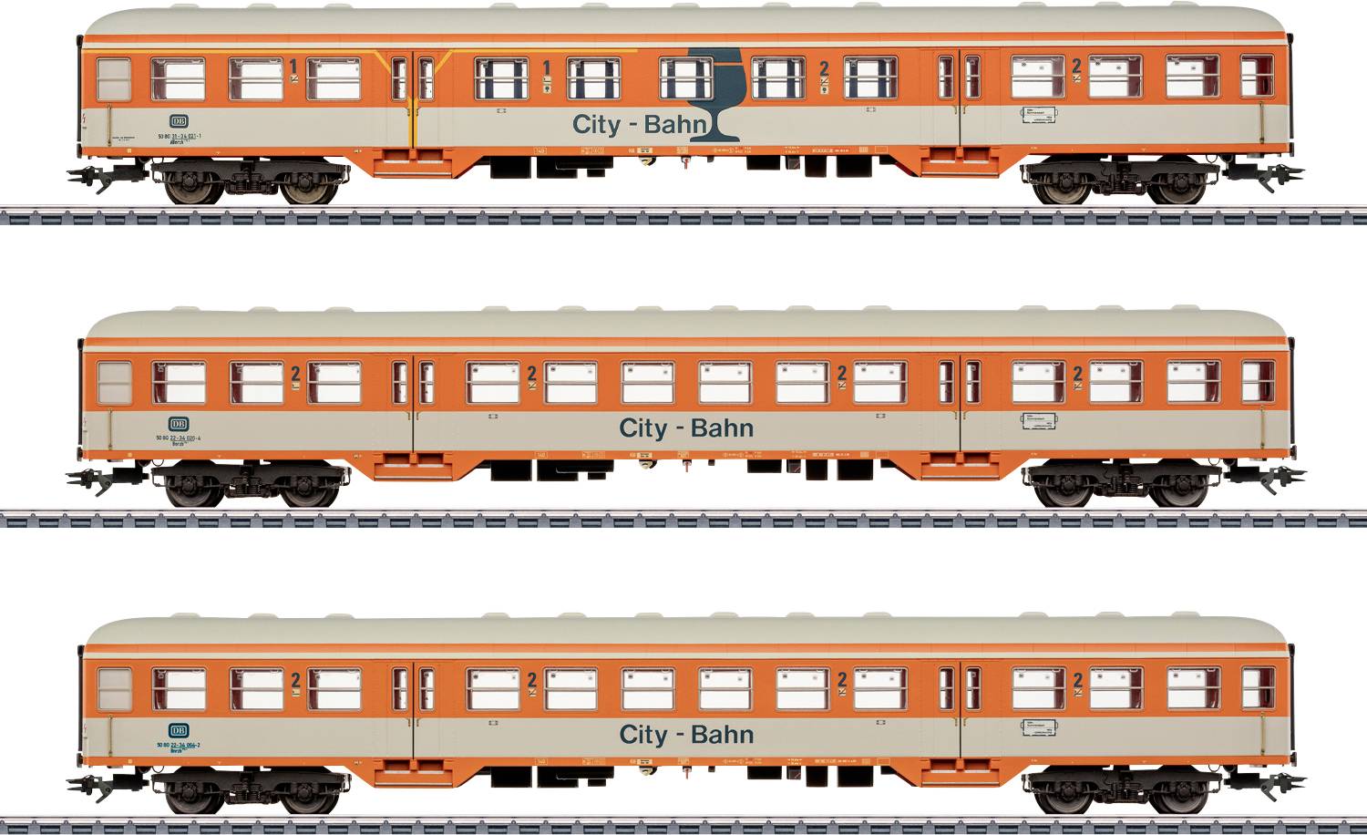 Trois voitures de train City-Bahn orange et crème sur des rails, étiquetées « City - Bahn » avec divers petits logos, vues côte à côte.