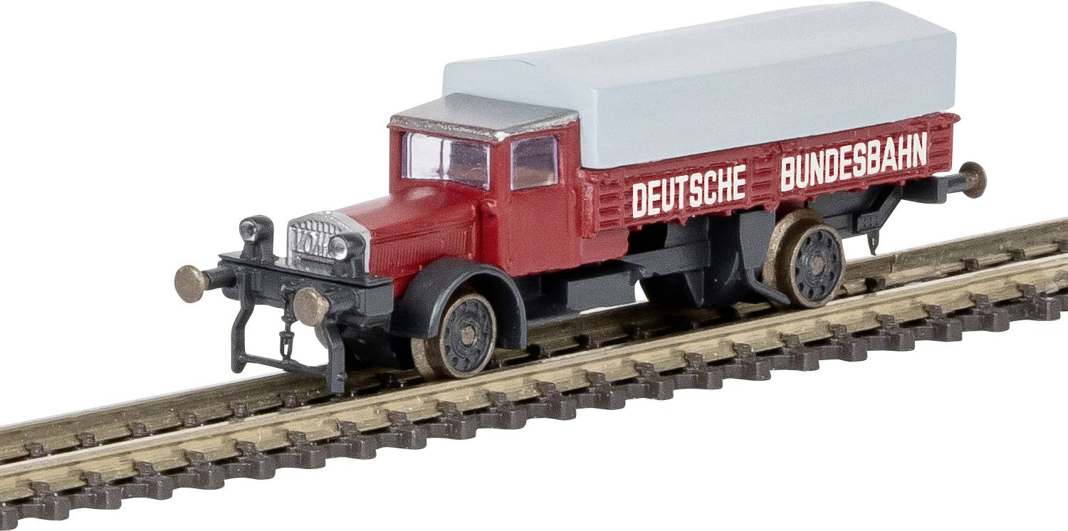 Un modèle miniature d'un camion vintage rouge et noir sur une voie ferrée, marqué « Deutsche Bundesbahn », avec une bâche gris clair à l'arrière.