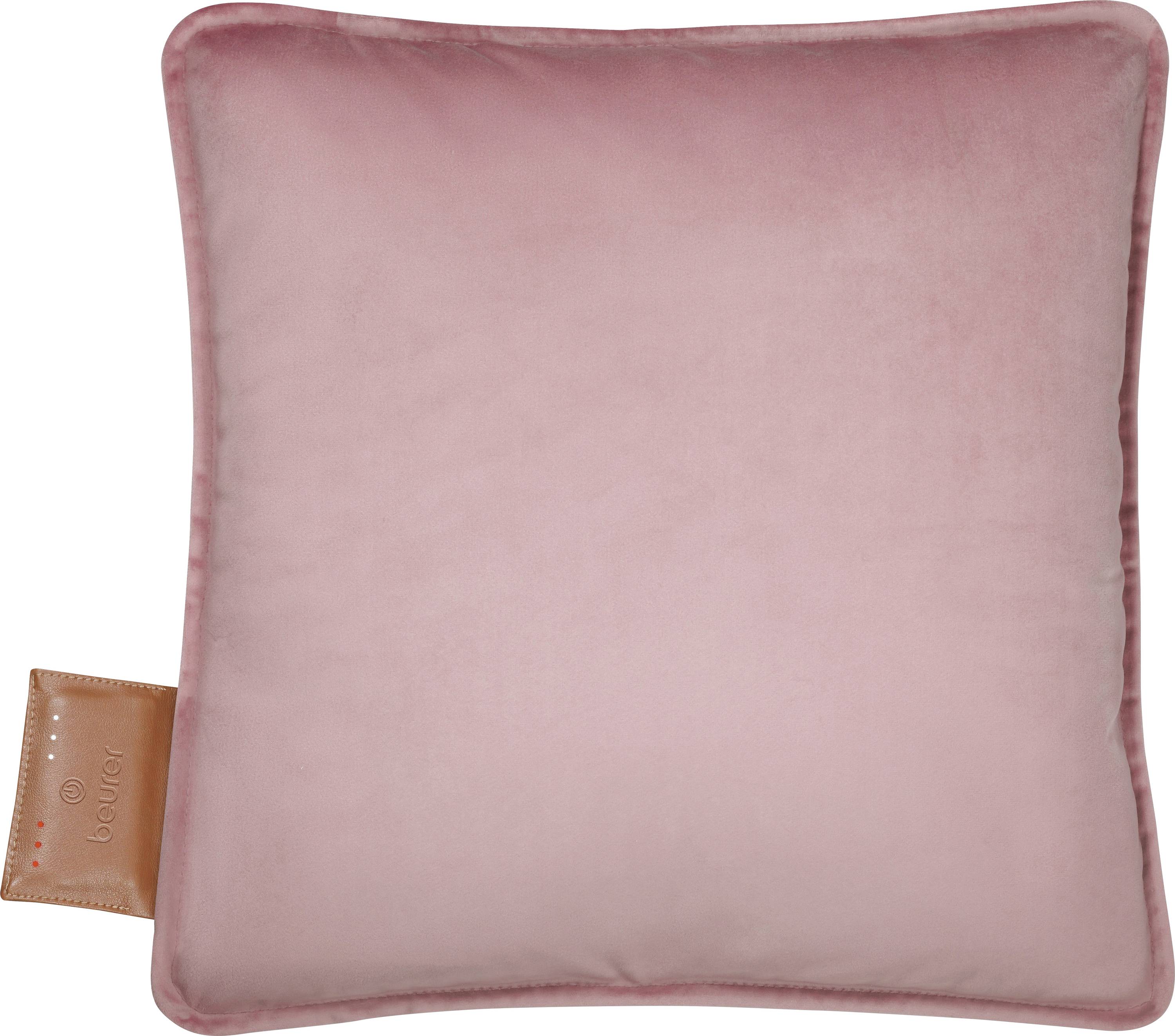 Un coussin carré en velours rose pâle clair avec une petite étiquette en cuir brun sur le côté.