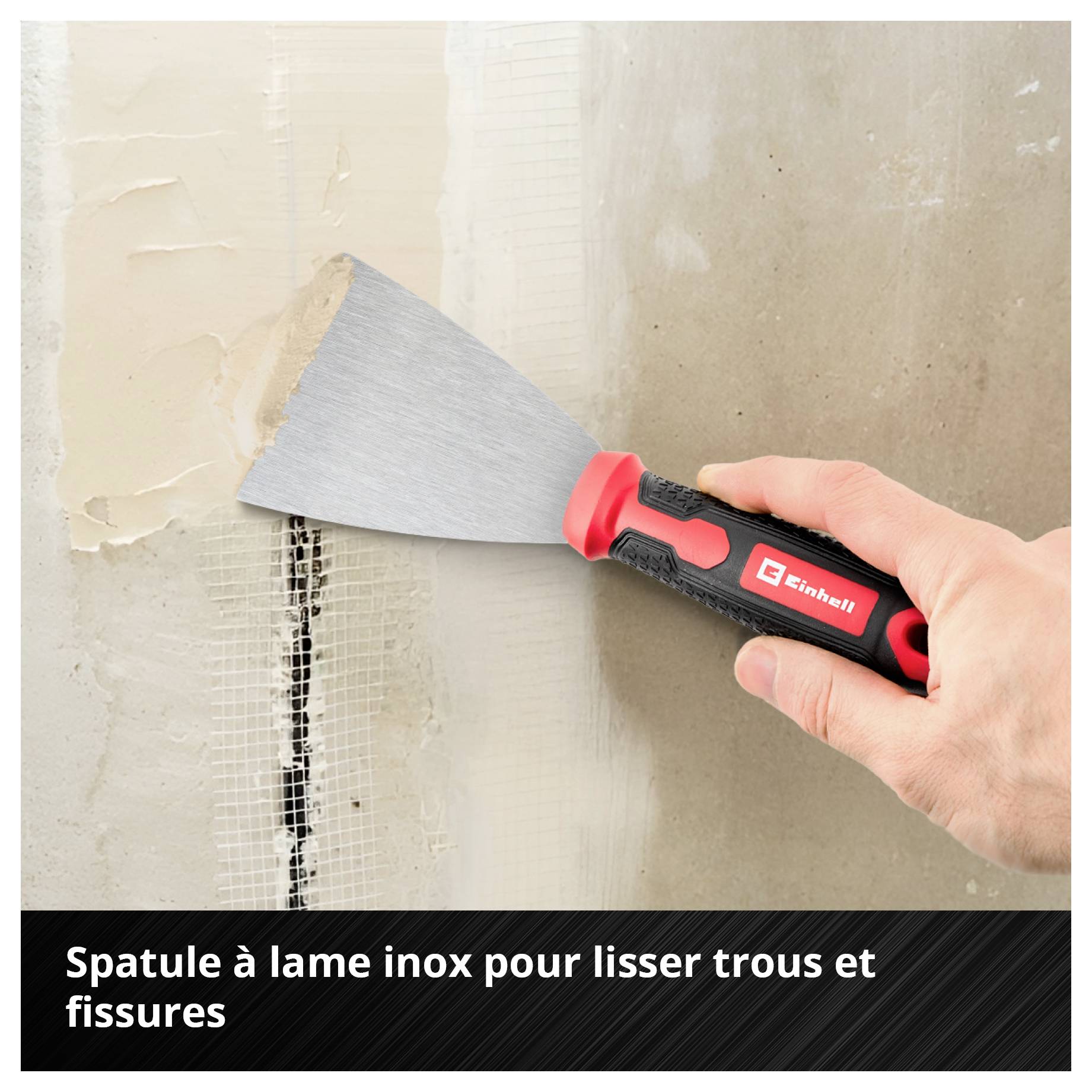 La main tient une spatule avec une lame en acier inoxydable, lisse les fissures dans le mur.