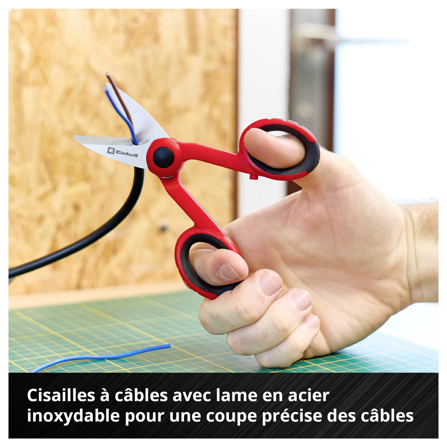 Hand hält rote Kabelschere, schneidet Kabel auf grünem Tisch. Text: 'Kabelschere mit rostfreier Edelstahlschneide für präzises Schneiden von Kabeln'.