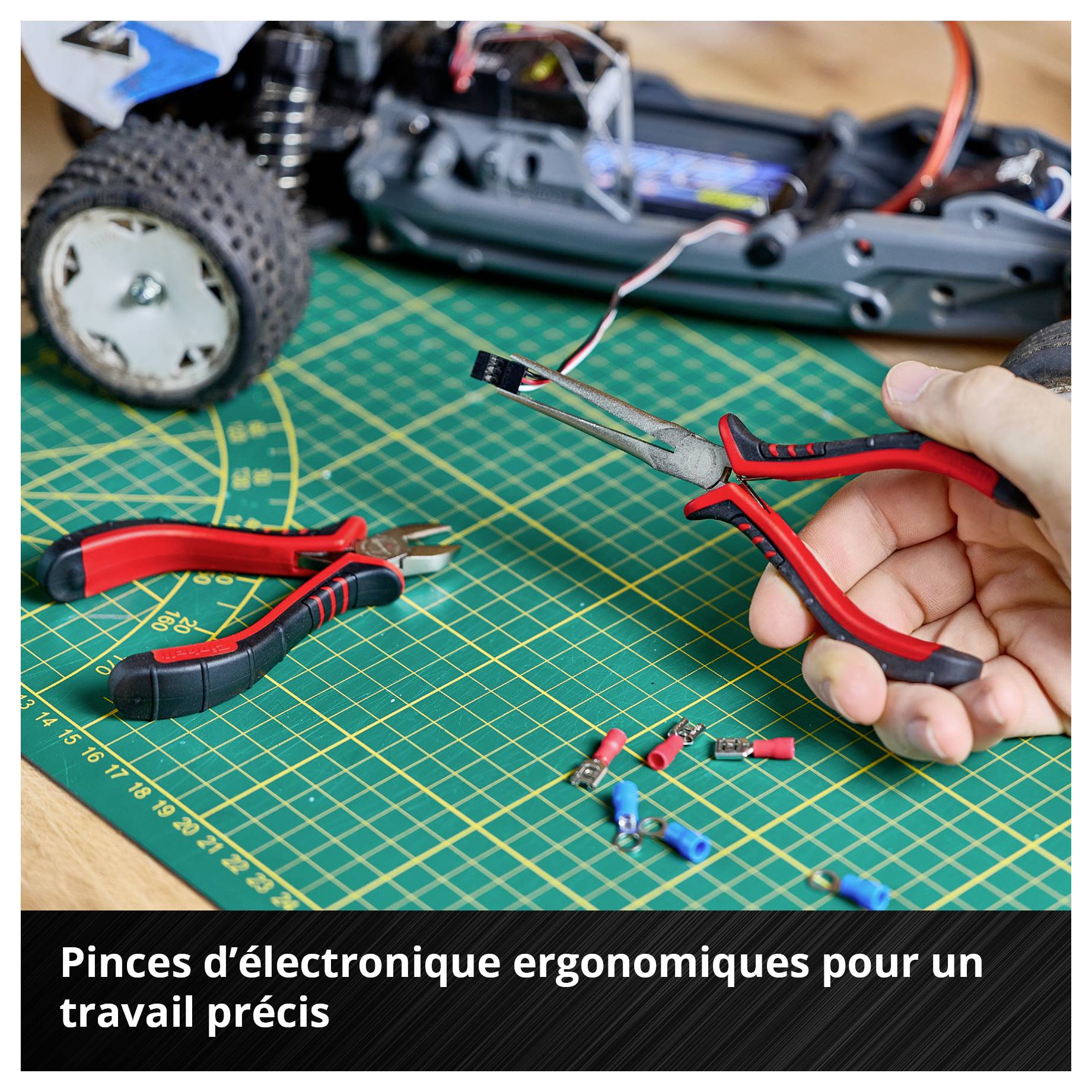 Établi avec voiture miniature, pinces d'électricien et câbles. Description : « Les pinces ergonomiques d'électricien facilitent un travail de précision ».
