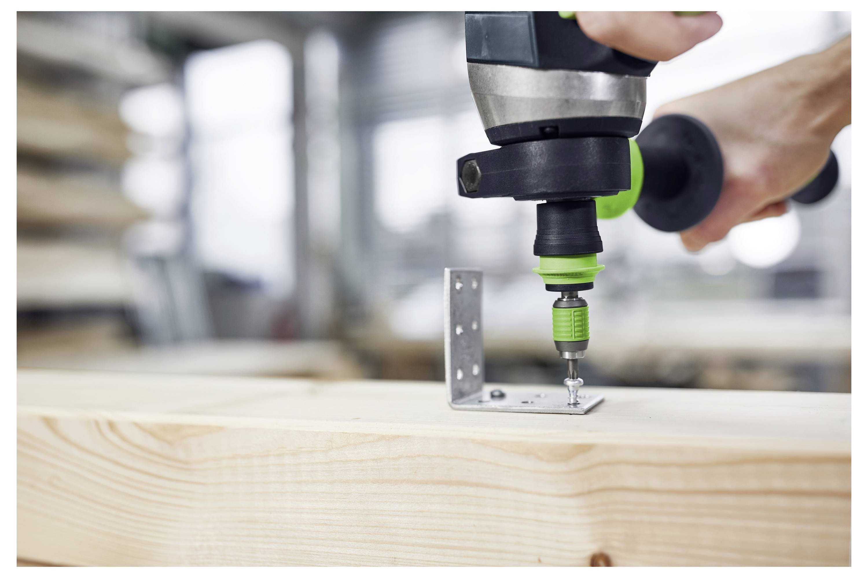 Une personne utilise une perceuse électrique pour fixer une équerre métallique à une planche de bois, indiquant une activité de menuiserie ou de construction.