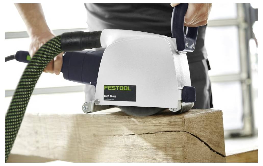 Une personne utilise une machine Festool BMS 180 E pour lisser la surface d'une poutre en bois ; un tuyau d'aspiration est attaché pour capturer la poussière.