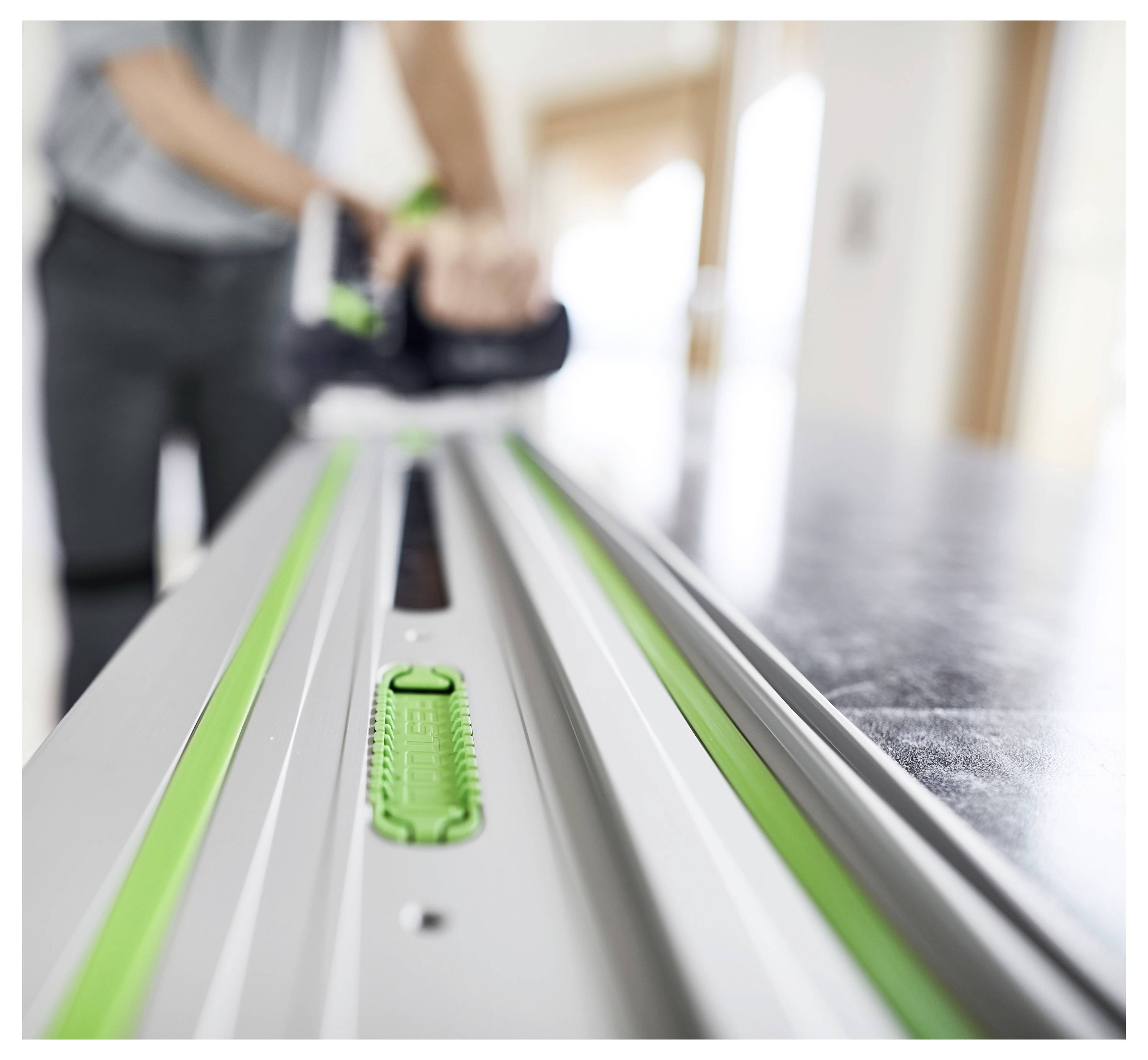 « Une personne utilise une scie circulaire sur rail sur un long rail de guidage métallique, en se concentrant sur des coupes de précision dans un espace de travail bien éclairé. »