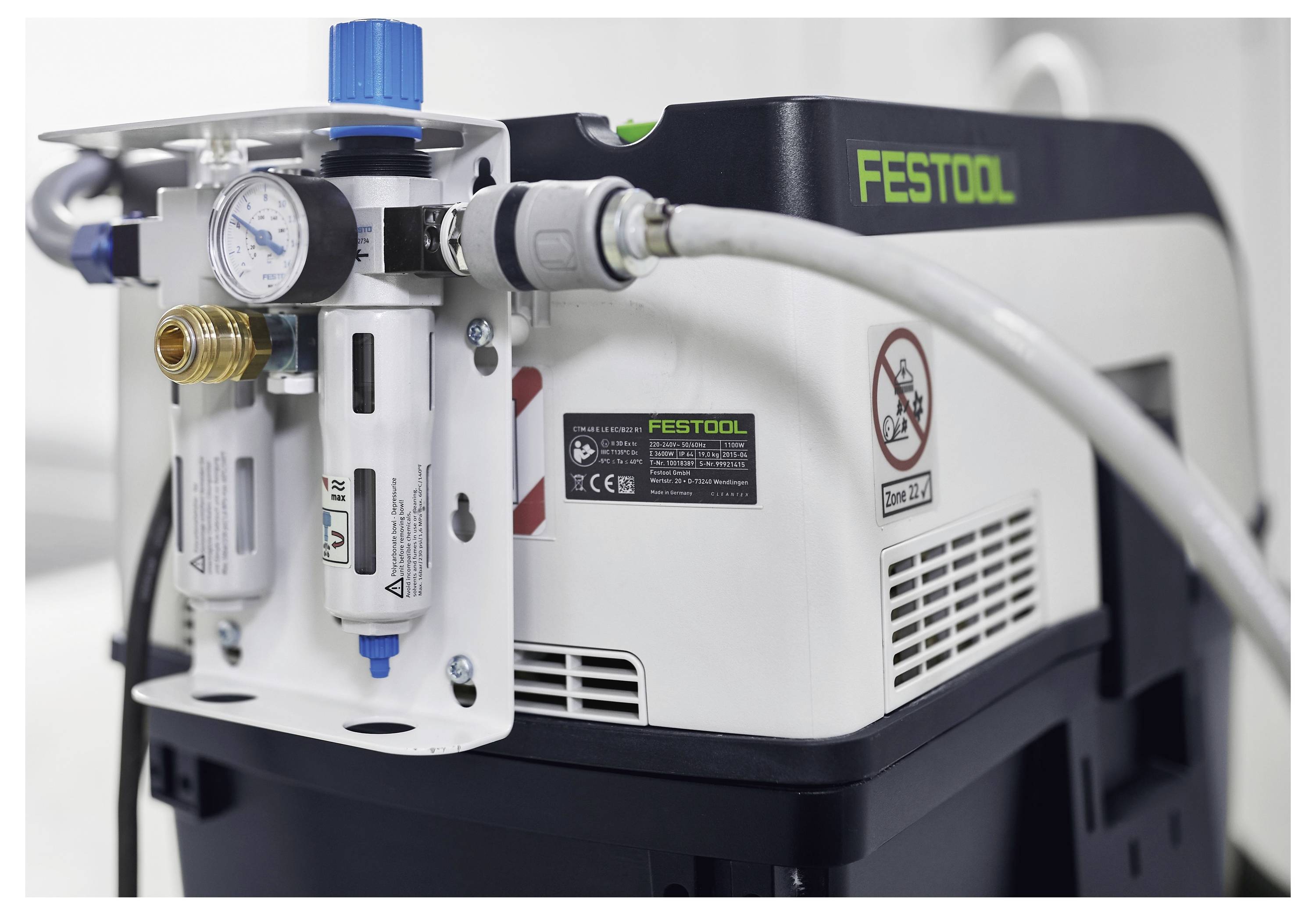 Gros plan d'une machine Festool avec un manomètre et des connecteurs, montrant un panneau « défense de fumer ».