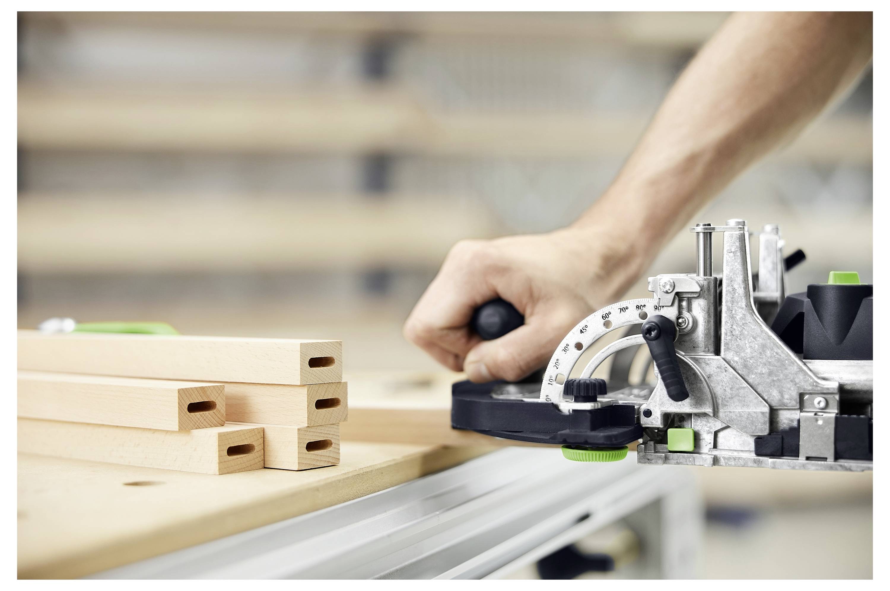 A person is using a woodworking tool to create precise joints in light wood beams, indicating skilled craftsmanship and attention to detail.