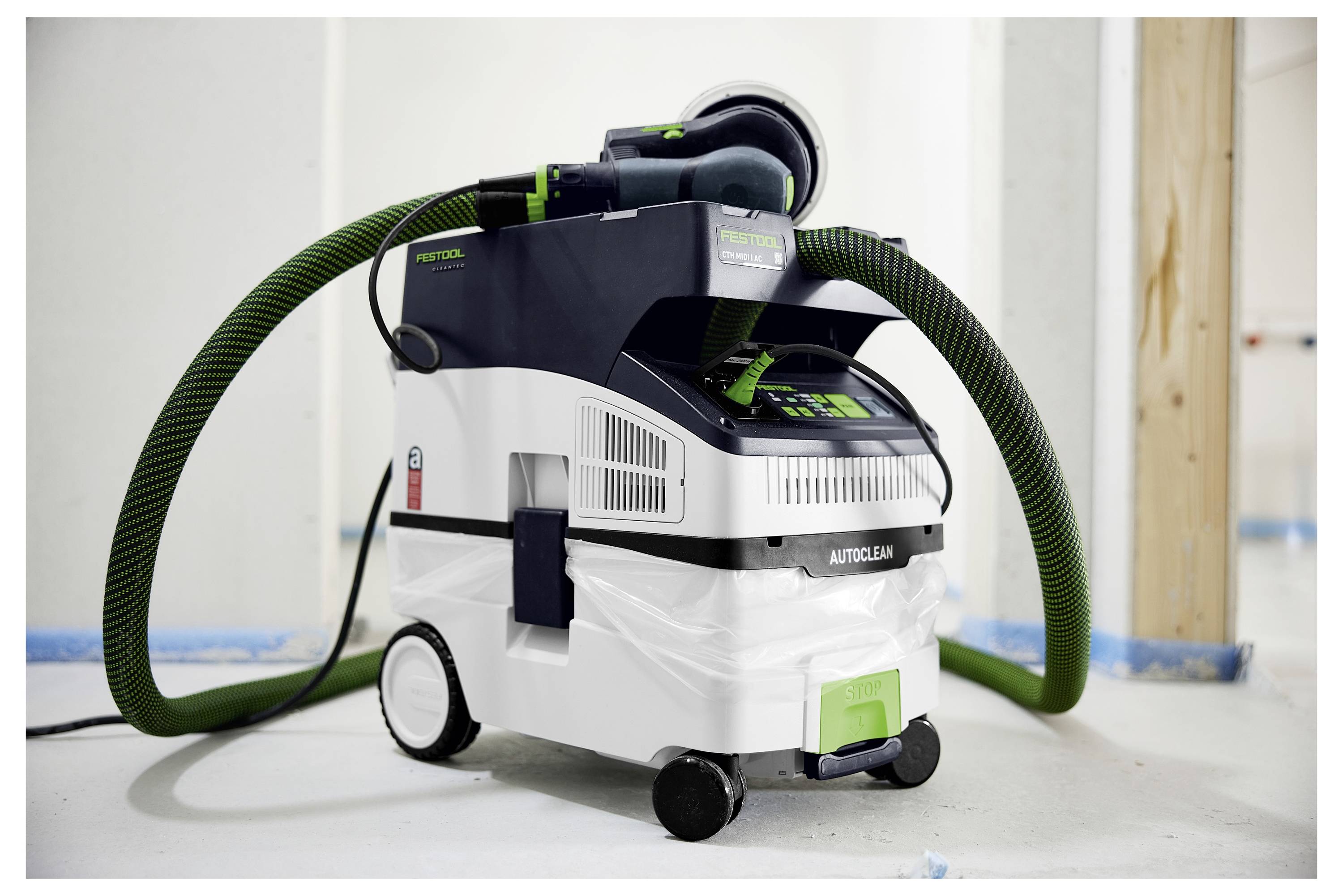 Mobile dust extractor on wheels with green hose and digital display, used for construction or renovation to maintain clean air.
