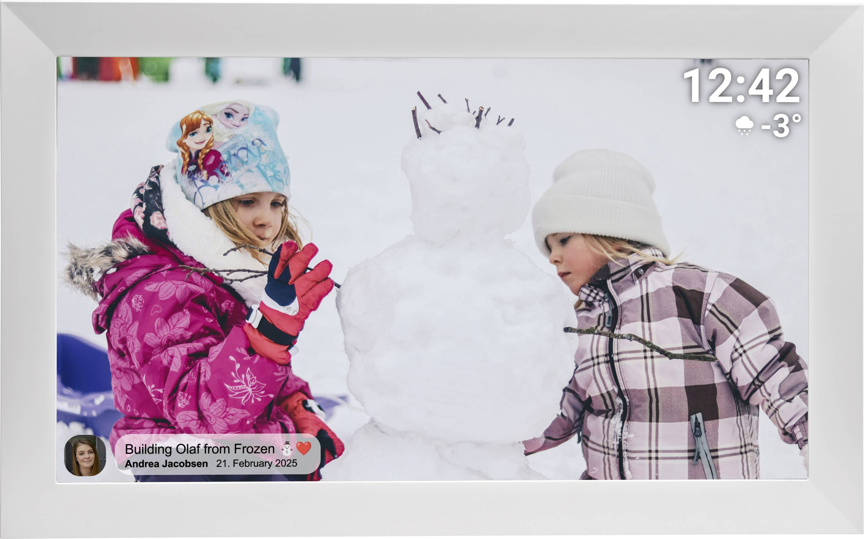 Deux enfants vêtus de vêtements d'hiver construisent un bonhomme de neige à l'extérieur. Un affichage numérique indique l'heure « 12:42 » et la température « -3°C ».