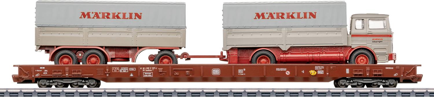 Un train miniature présente un wagon plat brun transportant un camion et une remorque, tous deux marqués « MARKLIN », sur une voie.