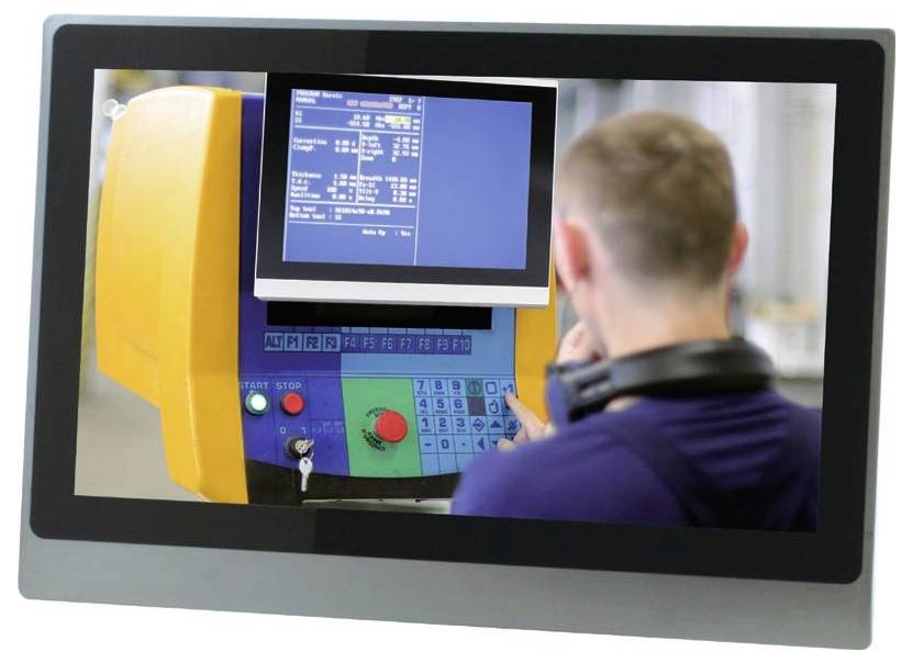 A person in a workspace operates a machine with a digital display showing technical data and controls the interface using keypad commands.