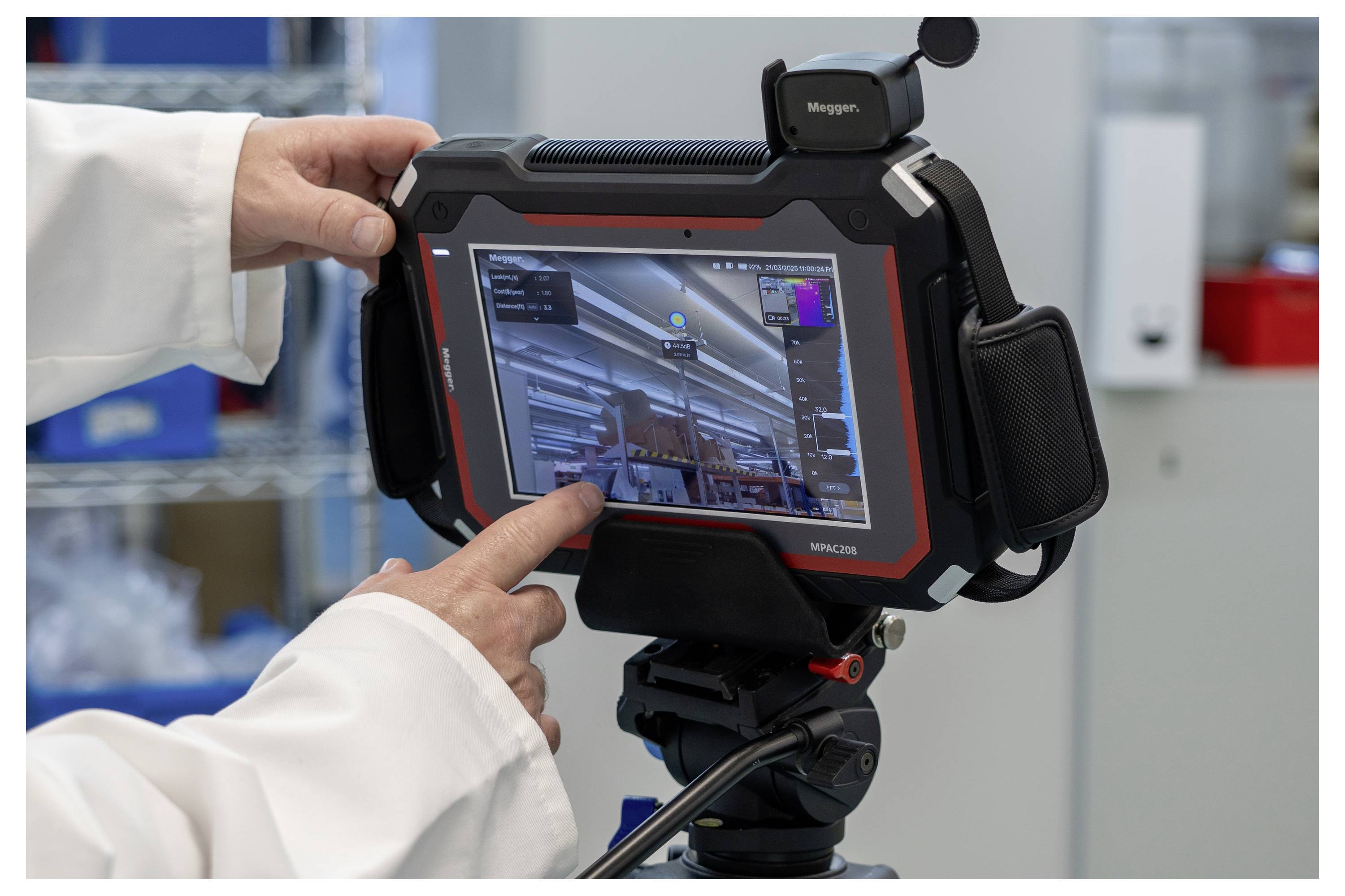 Une personne en blouse de laboratoire utilise une tablette fixée sur un trépied pour capturer des images ou des données dans un environnement de laboratoire.