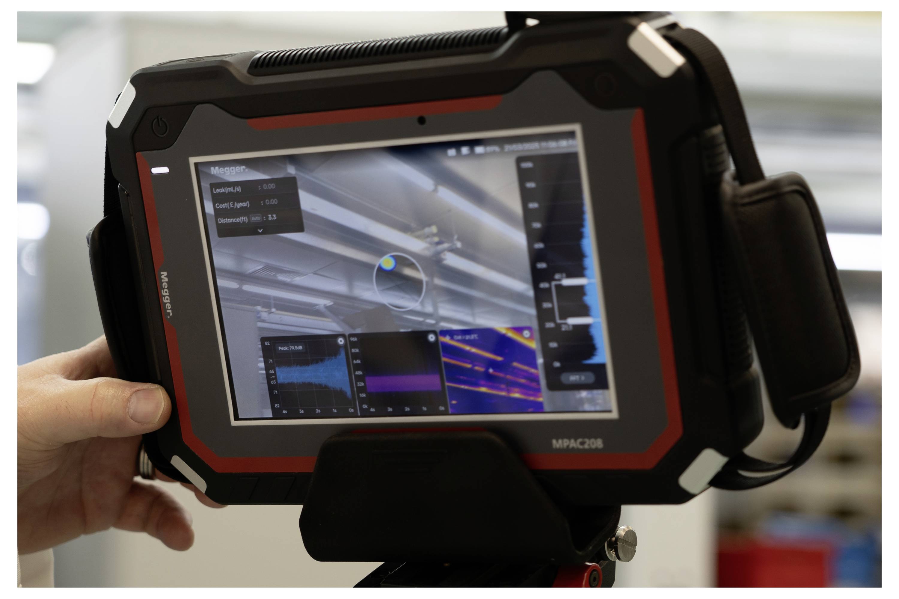 Une personne tient une tablette robuste affichant un logiciel d'imagerie thermique avec des graphiques et des données, probablement utilisée pour l'inspection d'équipements ou de bâtiments.
