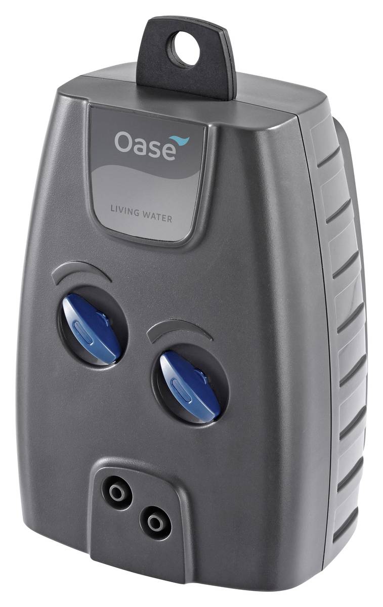 Gray Oase Living Water device with top hanging loop, two blue adjustment dials, and two outlet ports, shown front view.