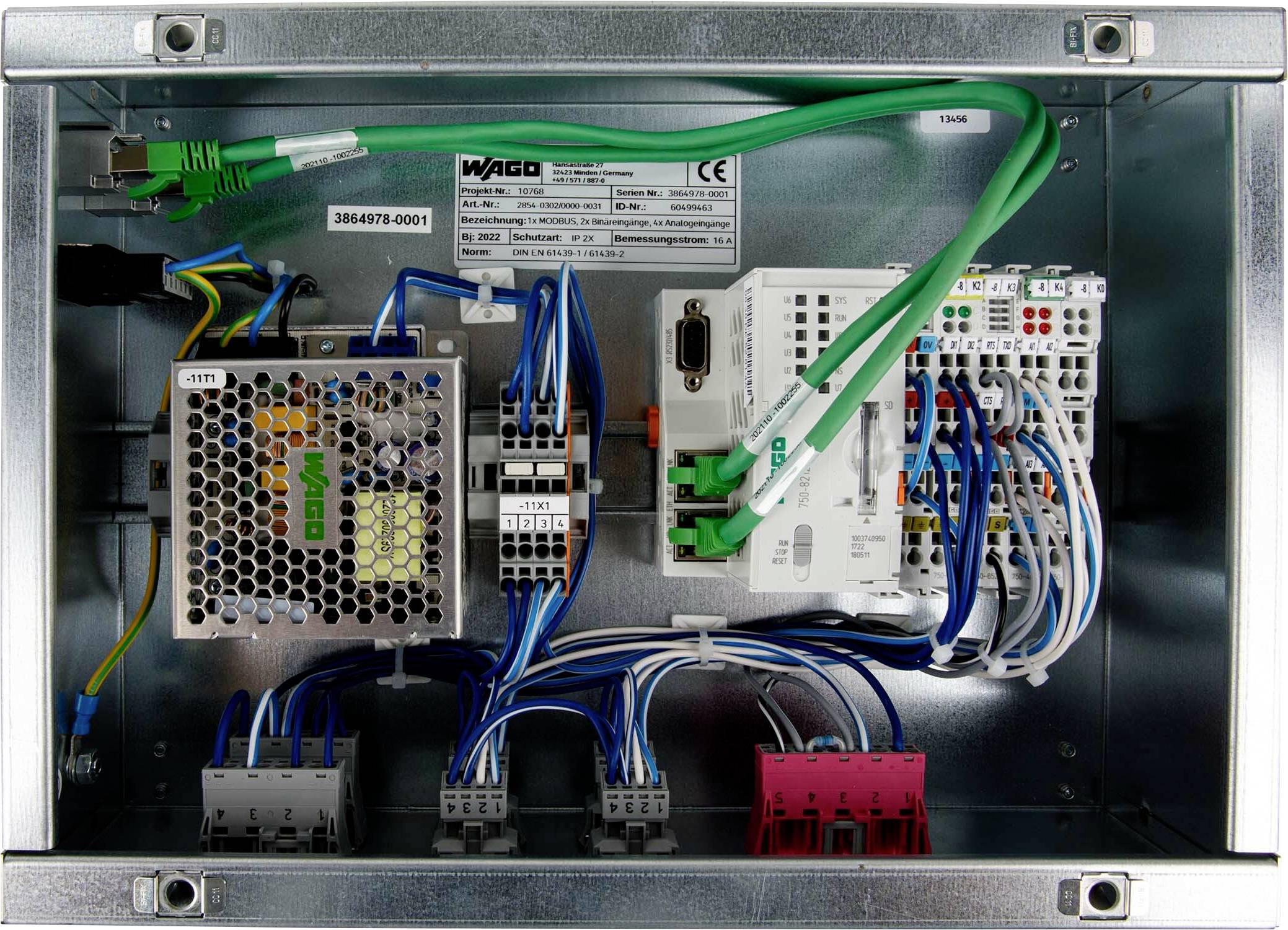 « Boîtier métallique contenant divers composants électroniques, câbles et connecteurs. Comprend un appareil WiFi et une étiquette partiellement visible avec des chiffres. »