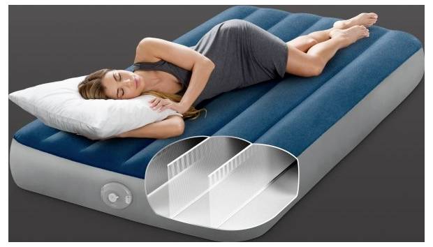 Une femme dort sur un matelas pneumatique gonflable bleu et gris avec une structure de support interne visible, illustrant le confort et la conception.