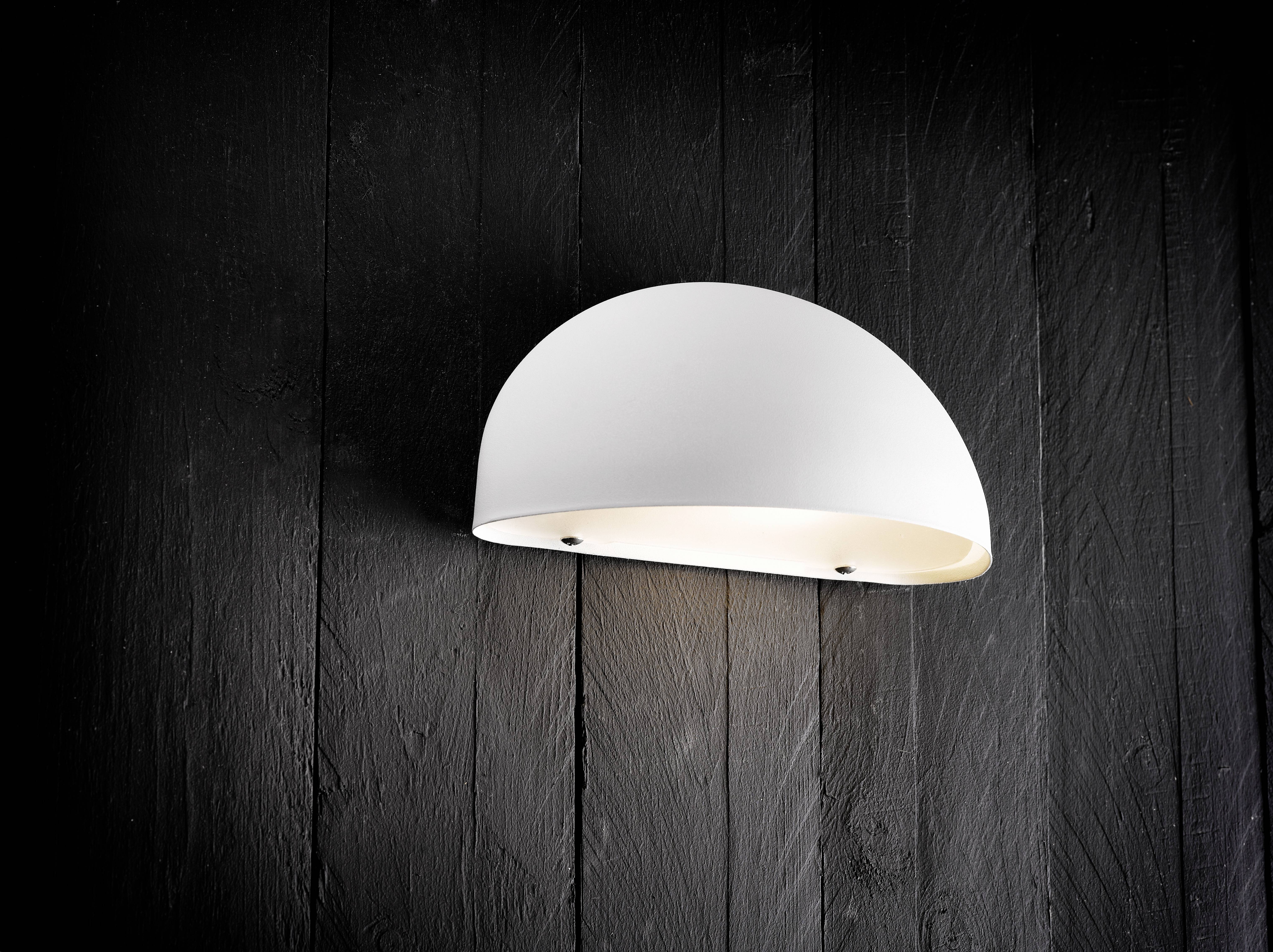 Une applique murale en demi-cercle de couleur blanche est montée sur un mur en bois foncé texturé, diffusant une lumière douce orientée vers le bas.
