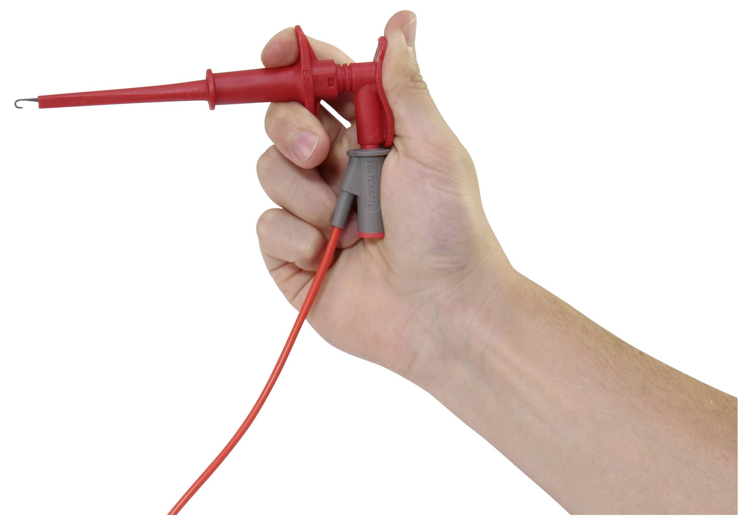 Hand holding a red multimeter probe with a red wire attached against a white background.