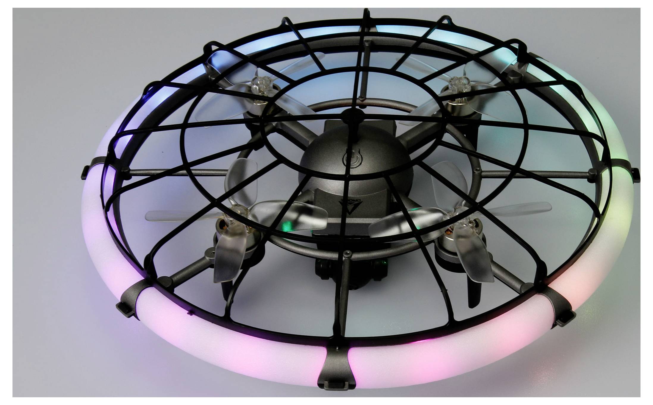 Un petit drone volant noir enfermé dans une cage de protection circulaire, avec des lumières LED roses et vertes brillantes autour du bord.