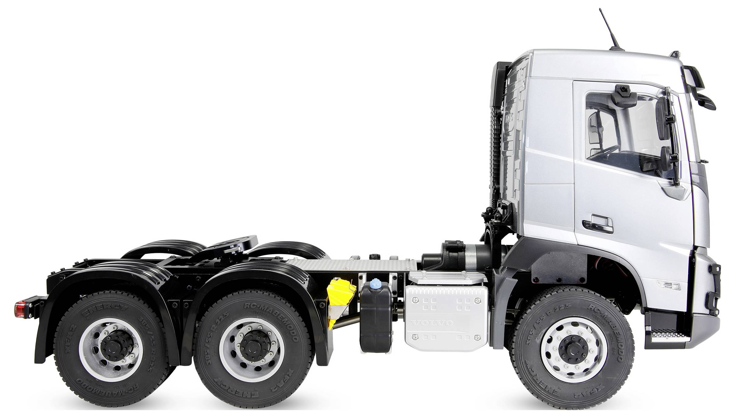 Vue latérale d'une cabine de semi-camion blanc sans remorque, montrant la cabine, le réservoir de carburant et plusieurs essieux arrière sur un fond blanc.