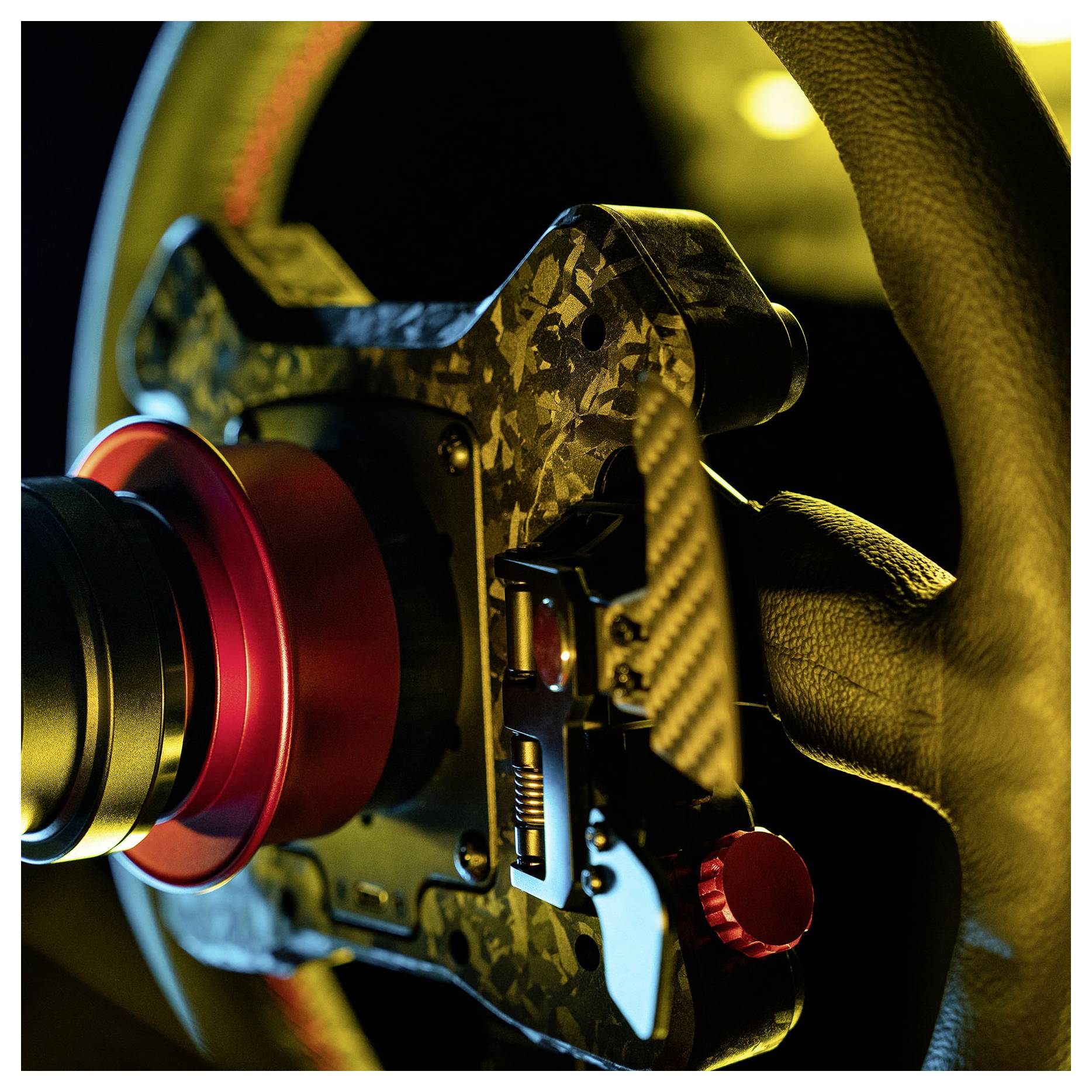 Gros plan d'un moyeu de volant de voiture de course avec un centre à dégagement rapide rouge, illuminé par un éclairage dramatique jaune et bleu.