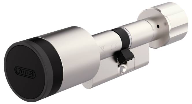 Gros plan d'un cylindre de serrure de porte cylindrique en argent avec un capuchon d'extrémité noir et du matériel de montage, présenté sur un fond blanc.