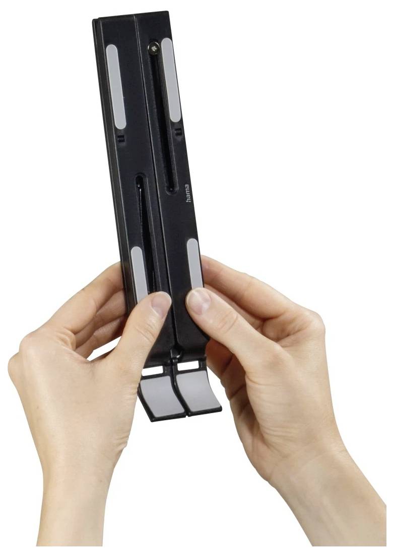 Hands holding a black plastic wall mount or bracket with adjustable slots, shown against a white background.