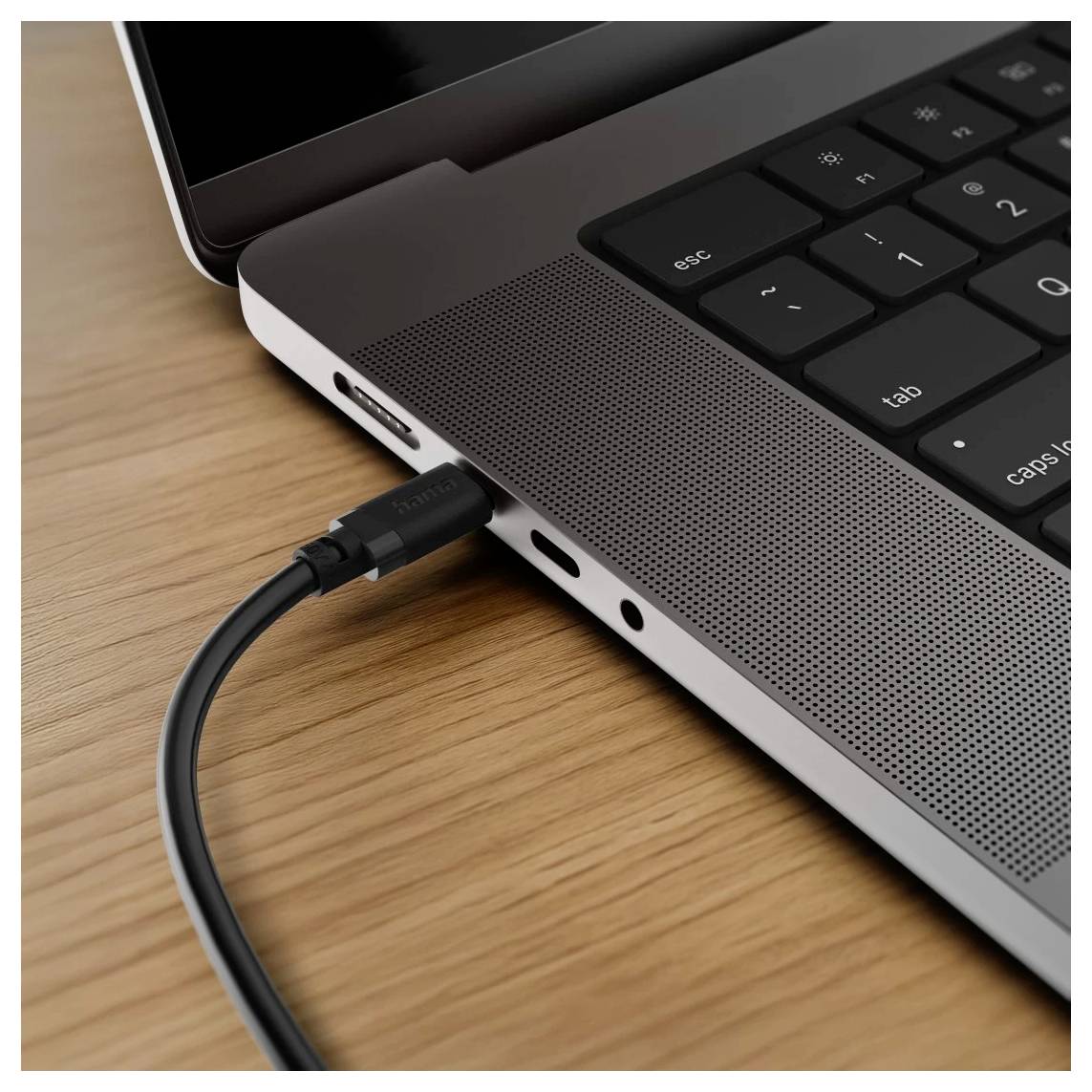 Câble USB-C branché sur le côté d'un ordinateur portable sur un bureau en bois.