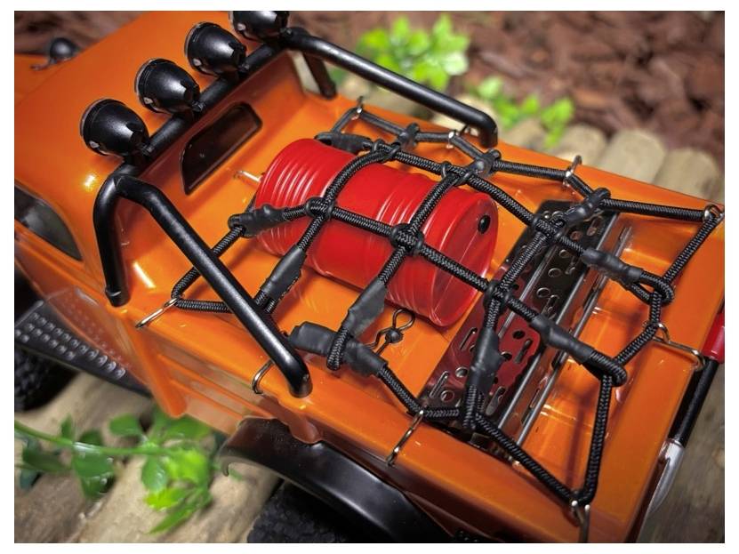 Gros plan d'un véhicule tout-terrain jouet avec carrosserie orange, échappement rouge et arceau de sécurité noir et porte-bagages, vu de dessus.