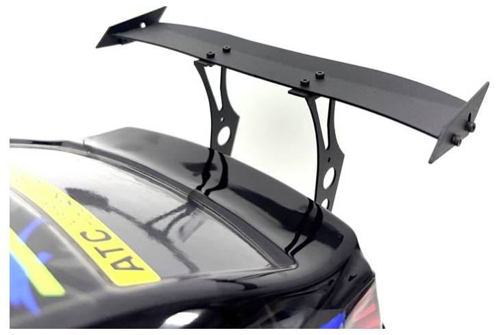 Aileron arrière noir monté sur le coffre d'une voiture de course pour un appui aérodynamique supplémentaire.