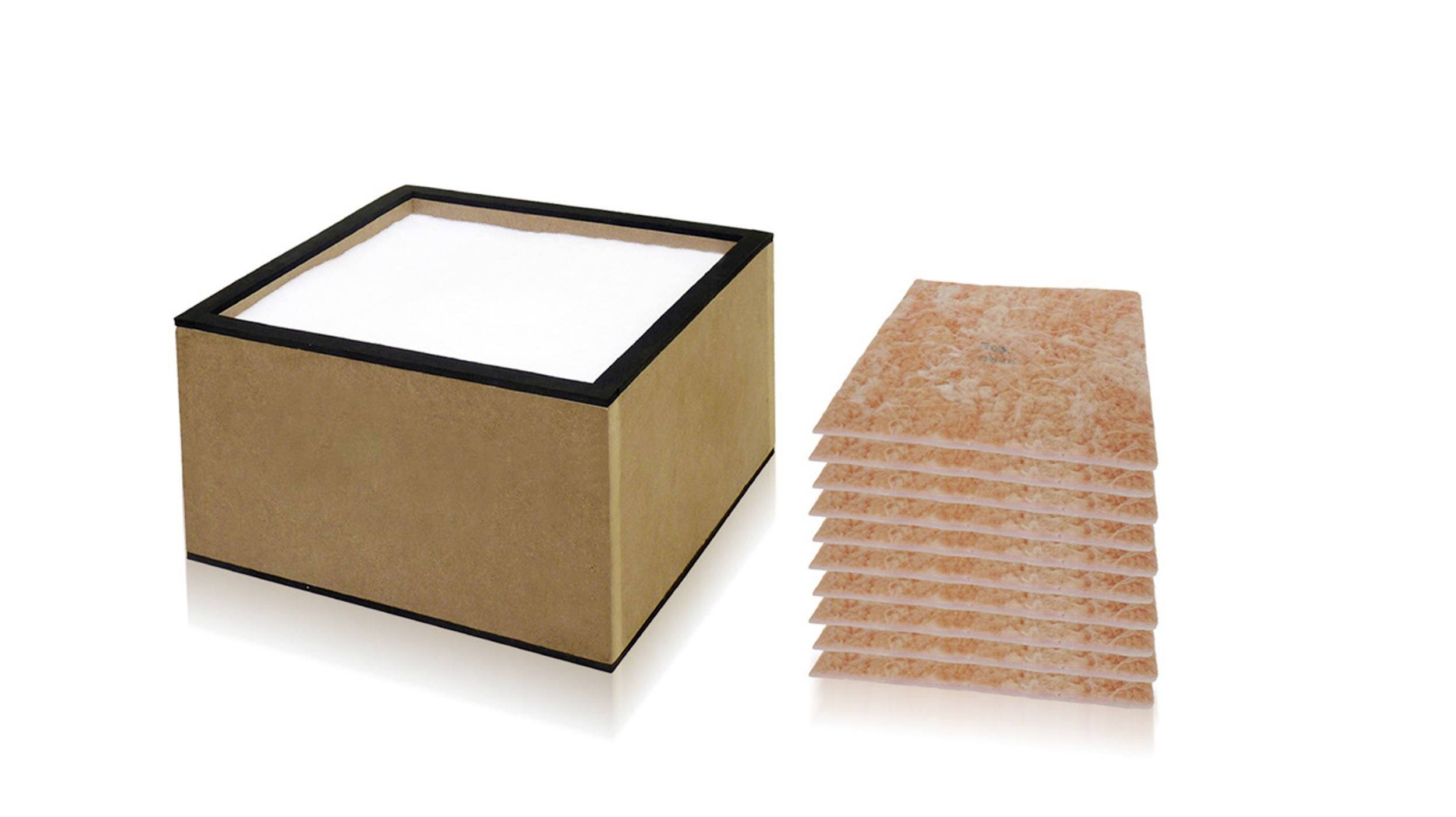 Cardboard box with a white-lined interior beside a neat stack of orange textured absorbent pads or tiles on a white background.